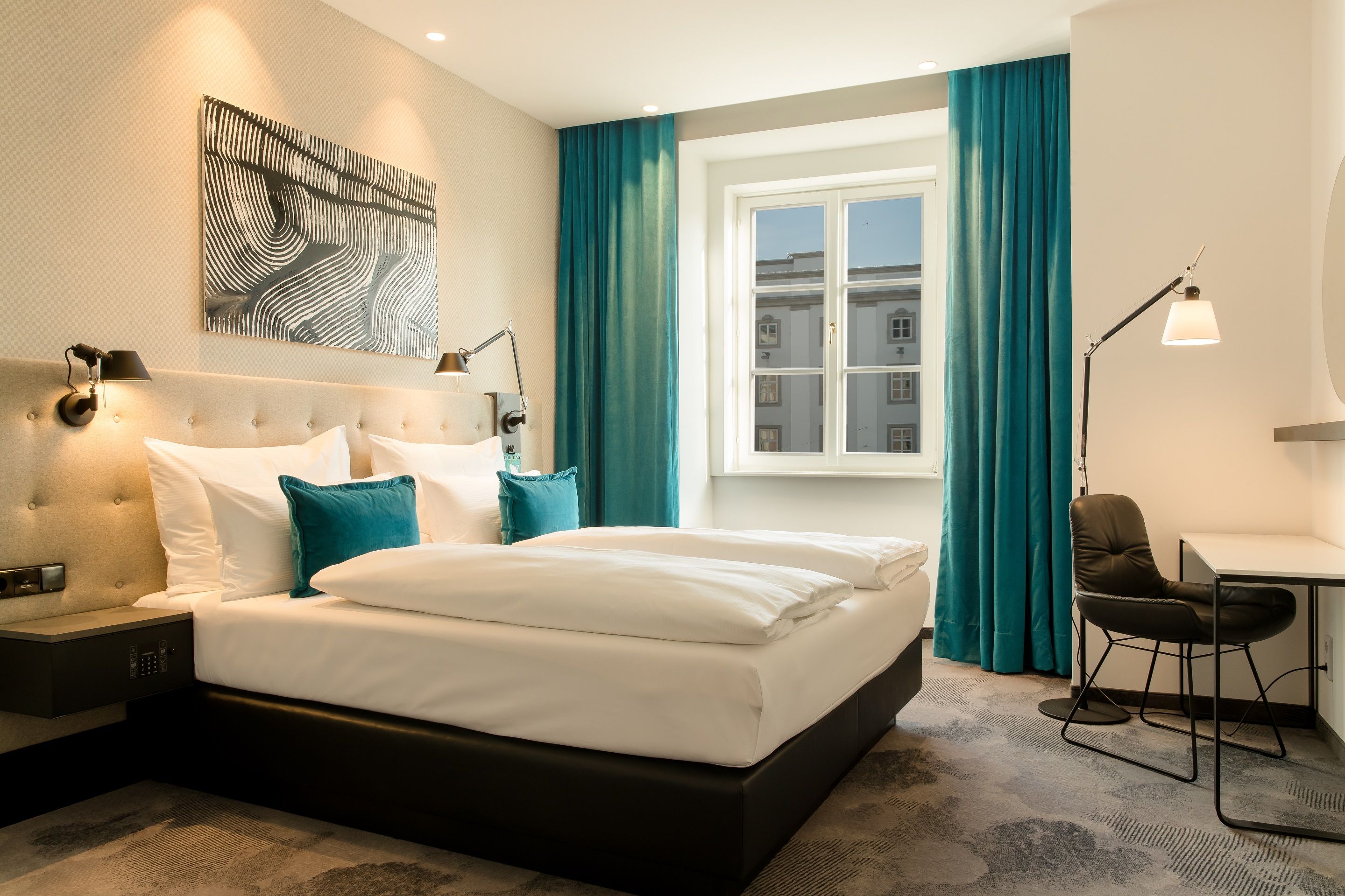 Designhotel Linz Hauptplatz Motel One seitlicher Blick in lichtdurchflutetes Doppelzimmer mit Schreibtisch und Stuhl