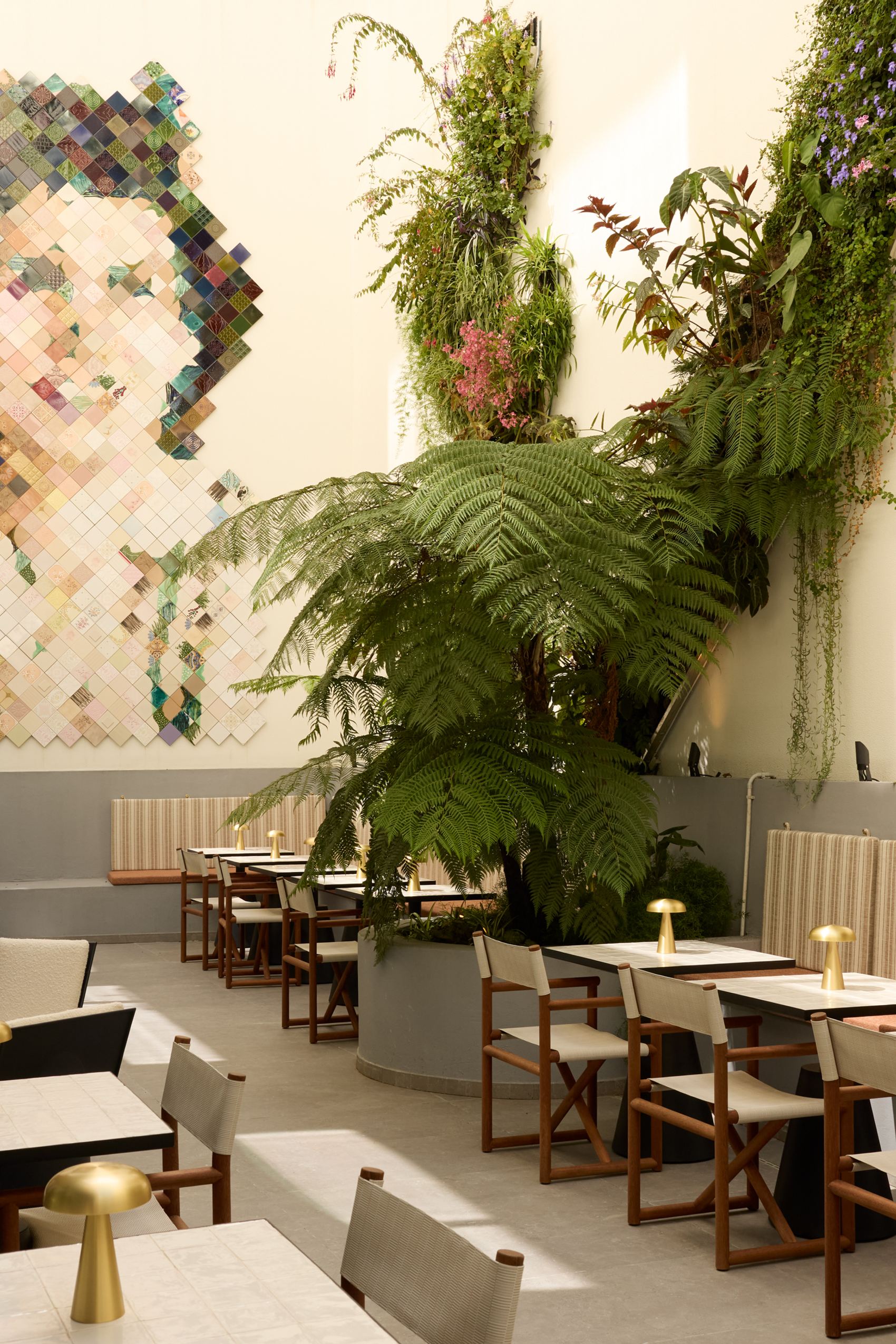 Hotel Lisbon The Cloud One bright courtyard with comfortable seating, green plants and a large mosaic mural depicting a face.