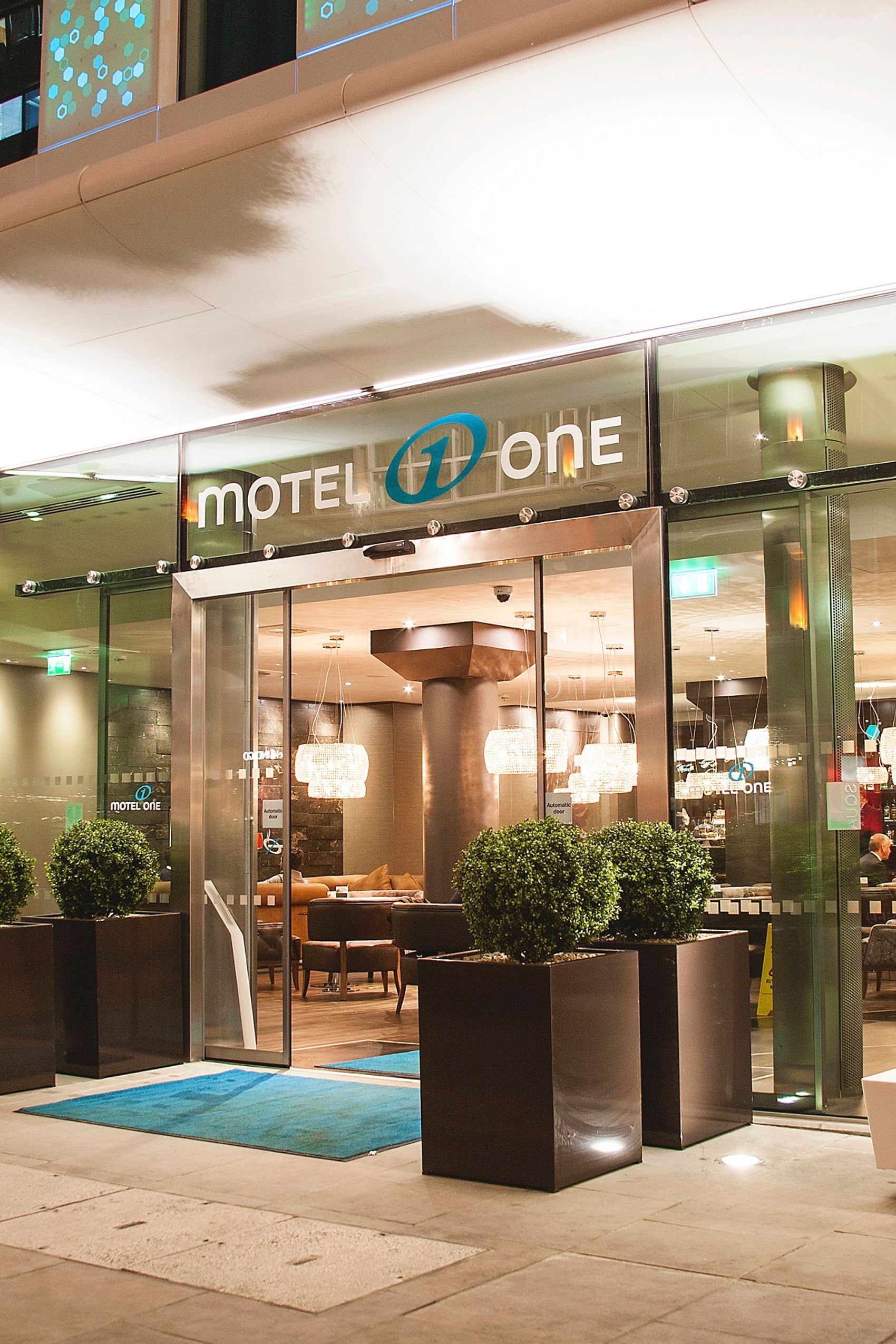 hotel London Tower Hill Motel One view from outside of the brightly lit entrance area at night