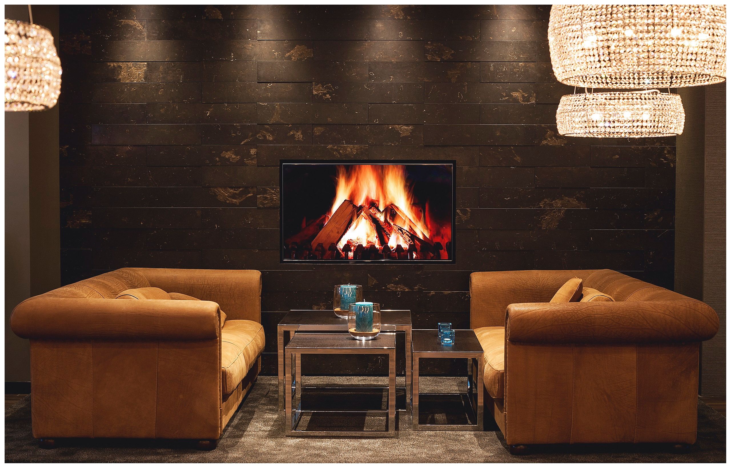 Designhotel London Tower Hill Motel One Lounge mit zwei Couches sowie TV mit Bild von Feuer in der Mitte