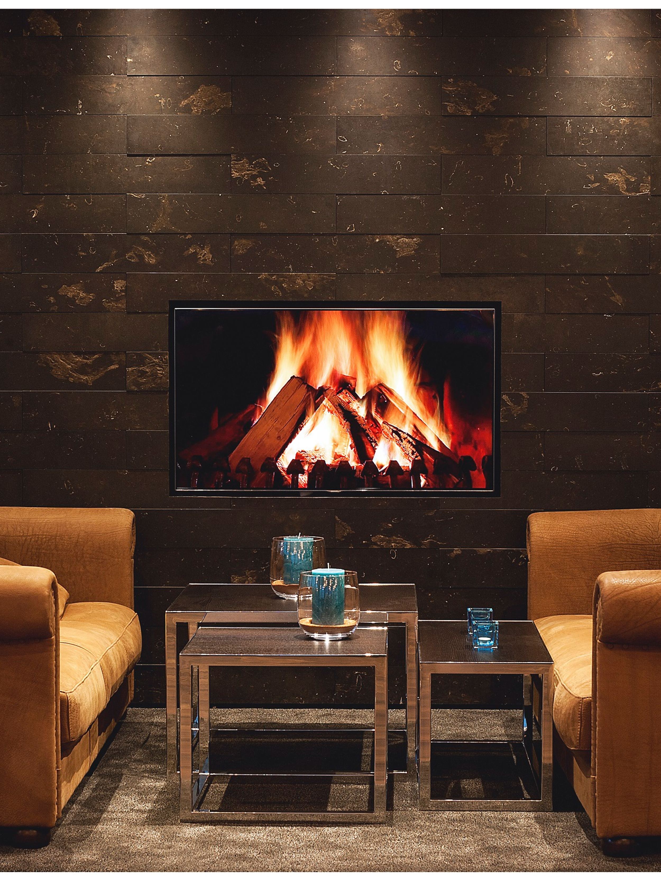 designhotel London Tower Hill Motel One lounge with two couches and TV with picture of fire in the center