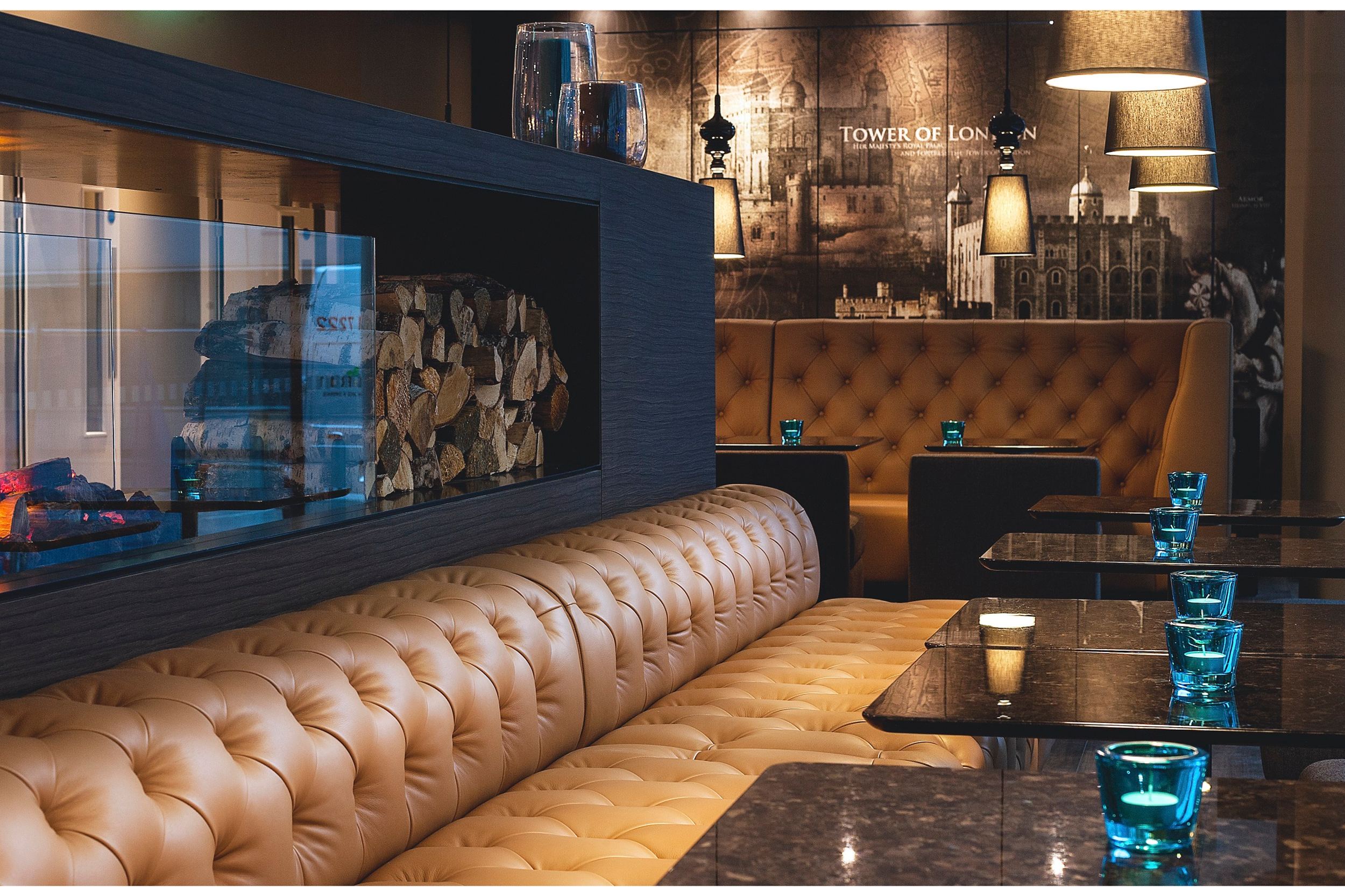 hotel London Tower Hill Motel One lounge with long couch, tables and open fire