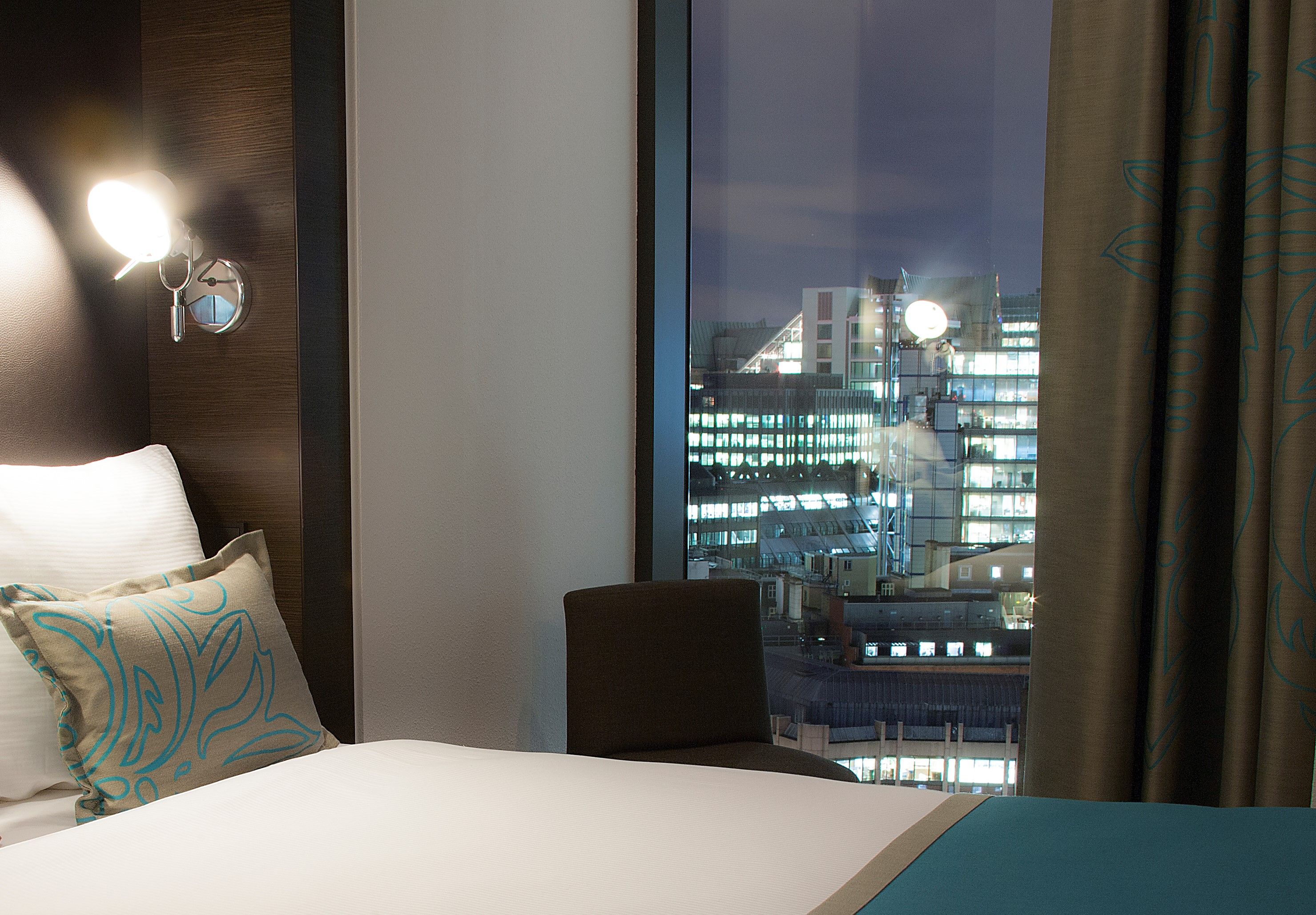 Designhotel London Tower Hill Motel One Zimmer mit Bett und Ausblick aus dem Fenster bei Abend