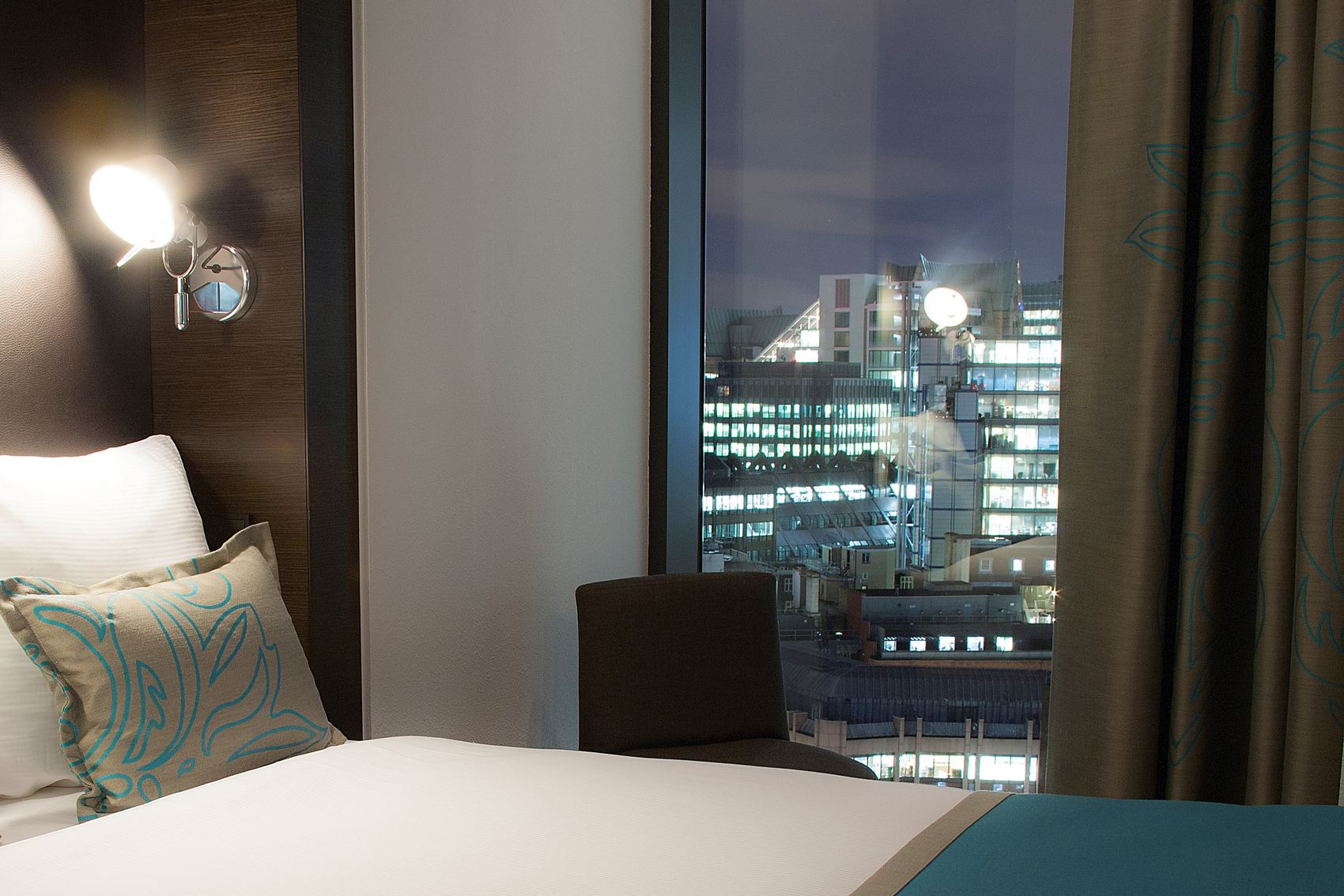 Designhotel London Tower Hill Motel One Zimmer mit Bett und Ausblick aus dem Fenster bei Abend