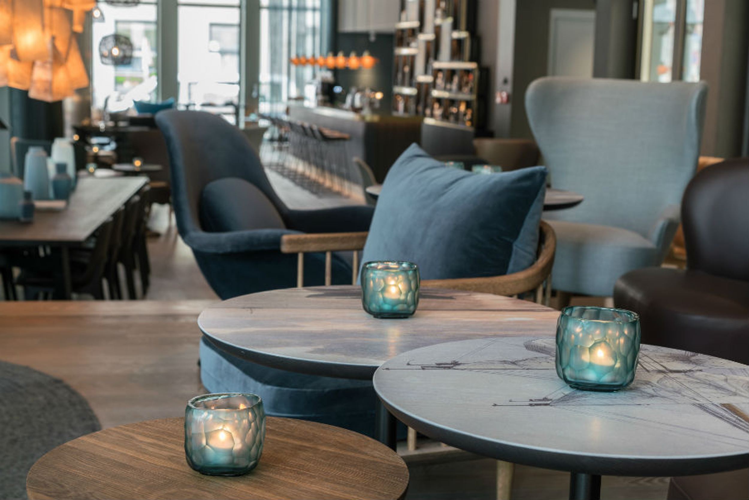 Hotel Lübeck Motel One Blick auf Tische und Sessel in der Lounge, im Hintergrund die Bar