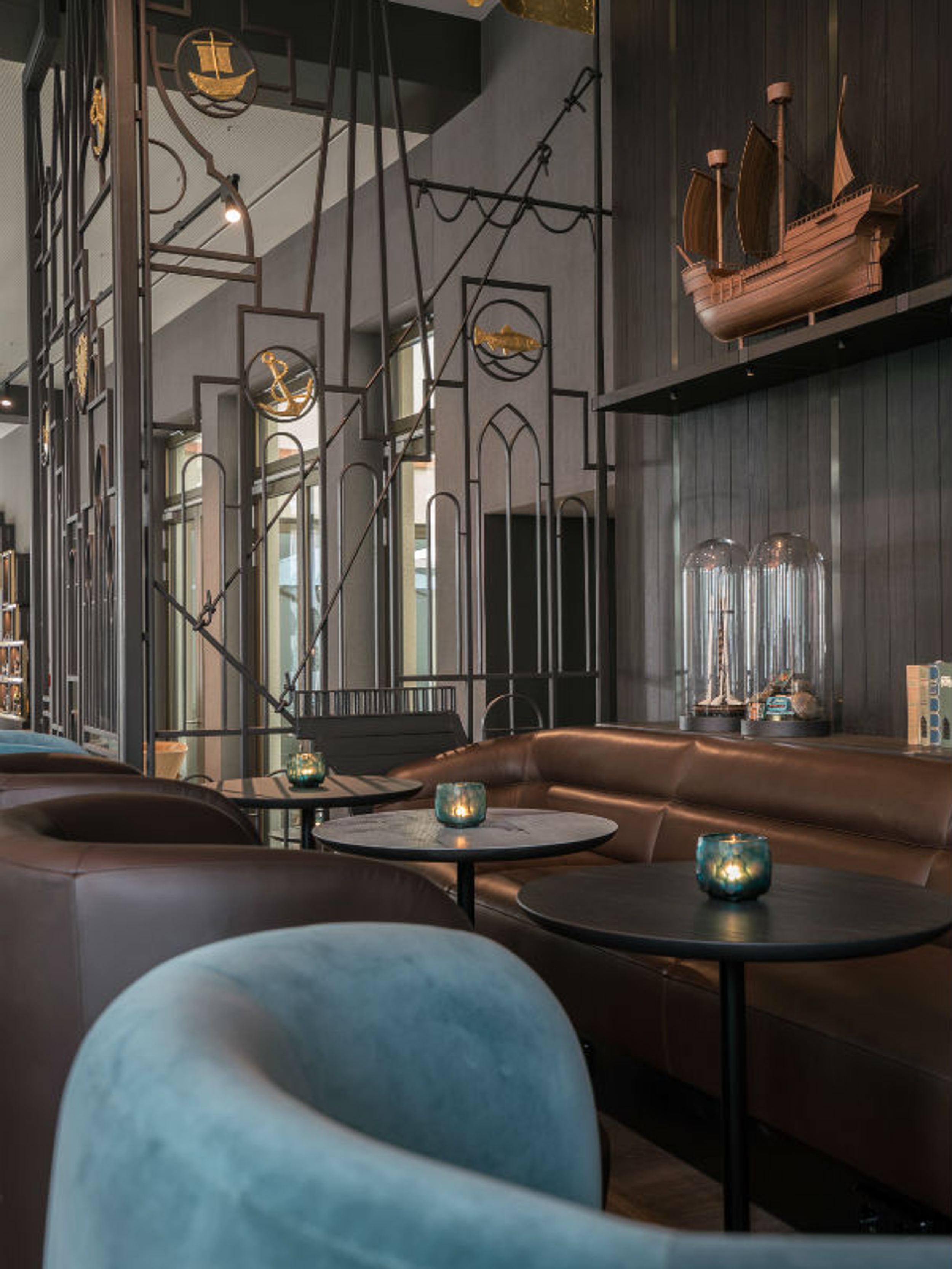 Hotel Lübeck Motel One helle Lounge mit Tischen und Sesseln auf der einen Seite sowie langer Couch