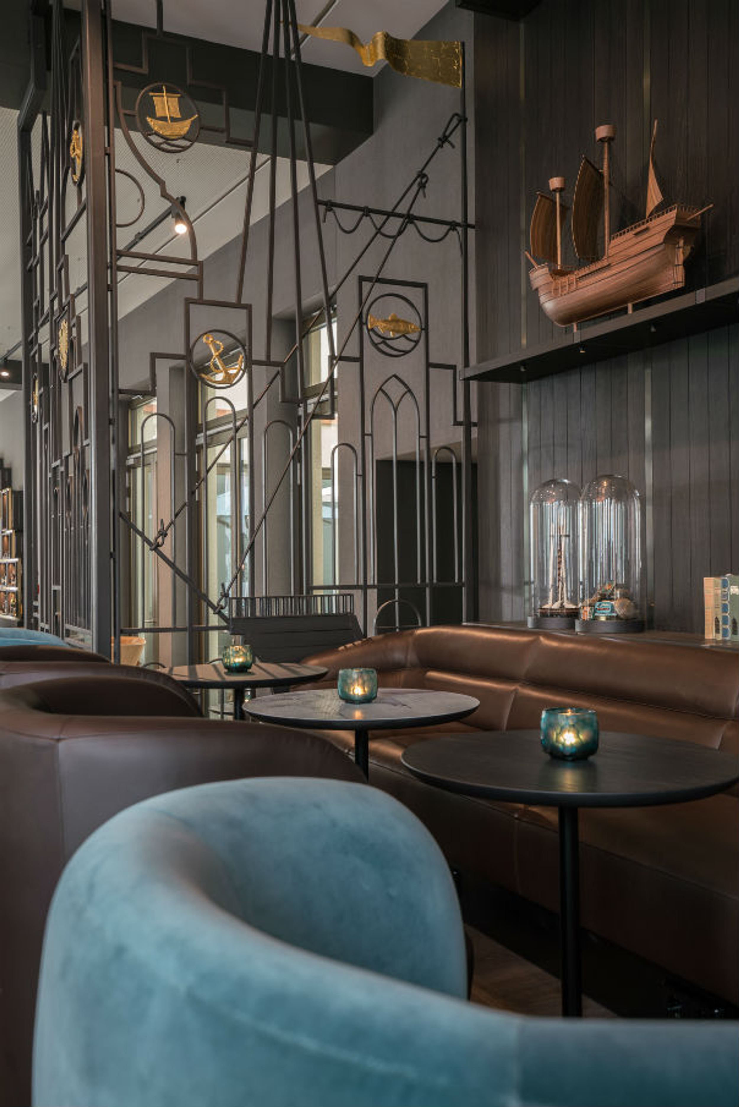 Hotel Lübeck Motel One helle Lounge mit Tischen und Sesseln auf der einen Seite sowie langer Couch