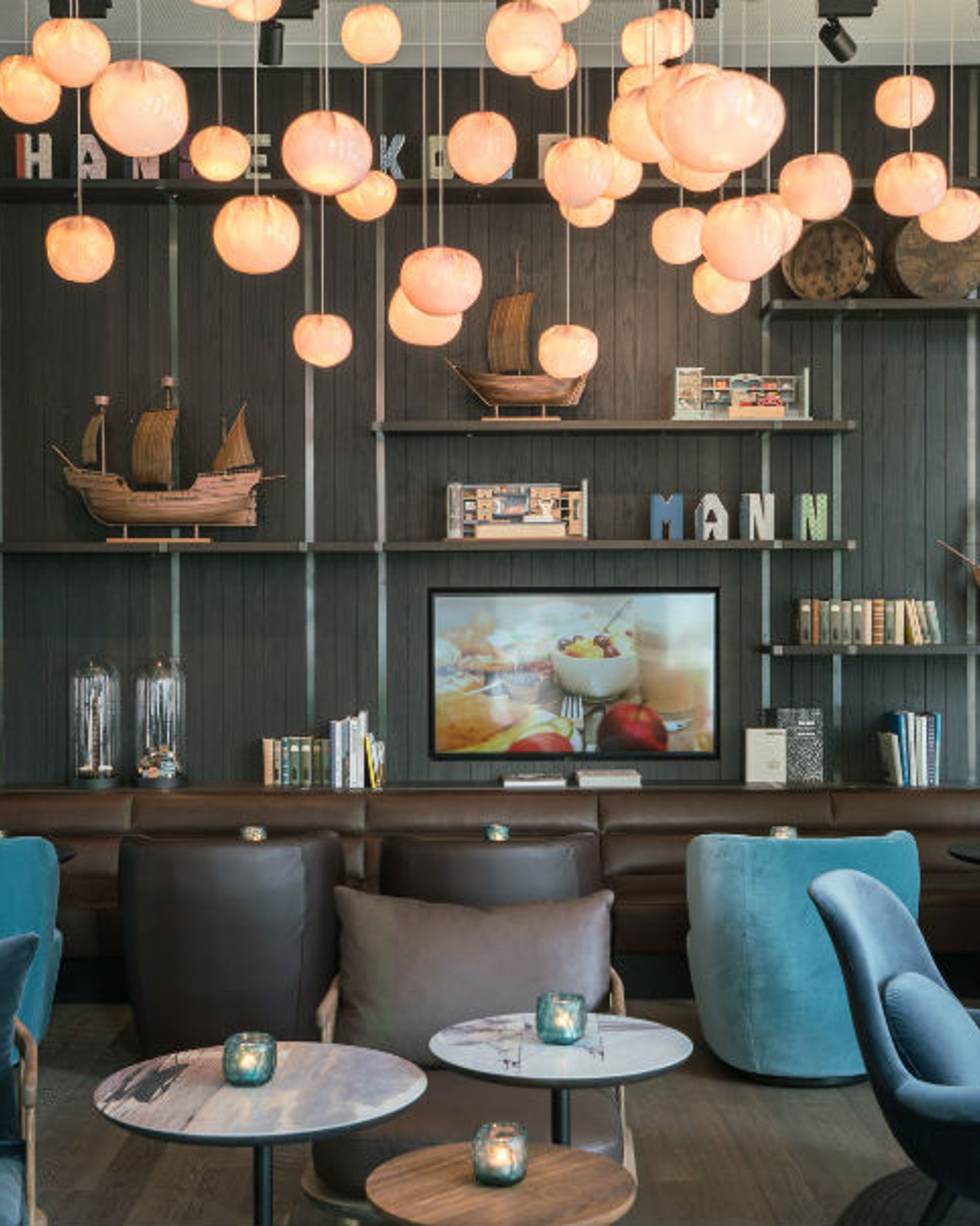 Hotel Lübeck Motel One Lounge mit Sesseln und großem Wandregal