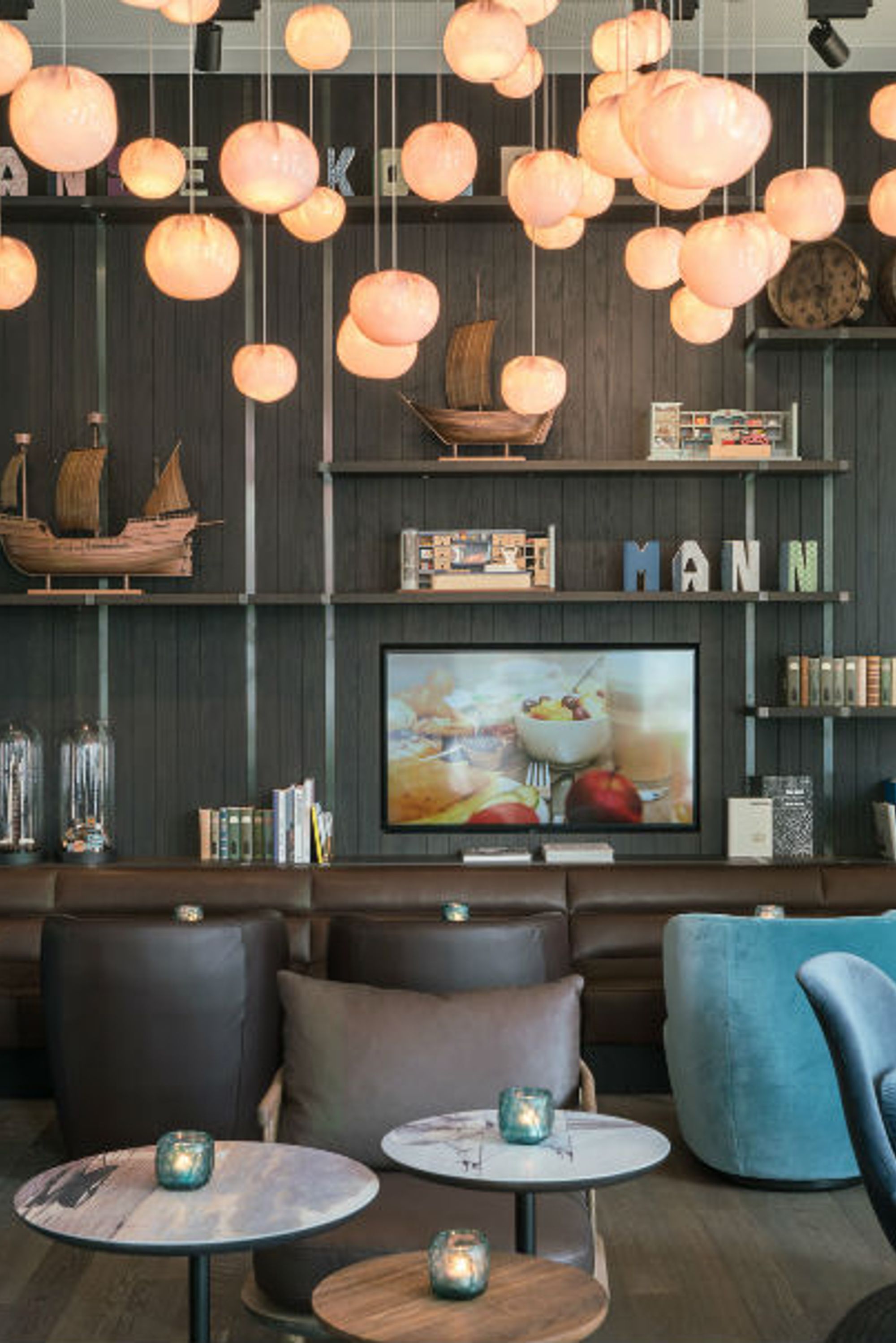 Hotel Lübeck Motel One Lounge mit Sesseln und großem Wandregal