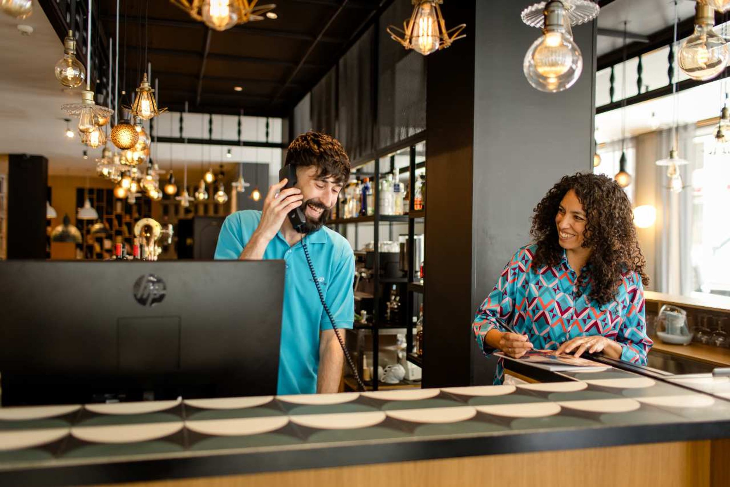 Designhotel Madrid Plaza de España Motel One Rezeption mit zwei lachenden Mitarbeitenden