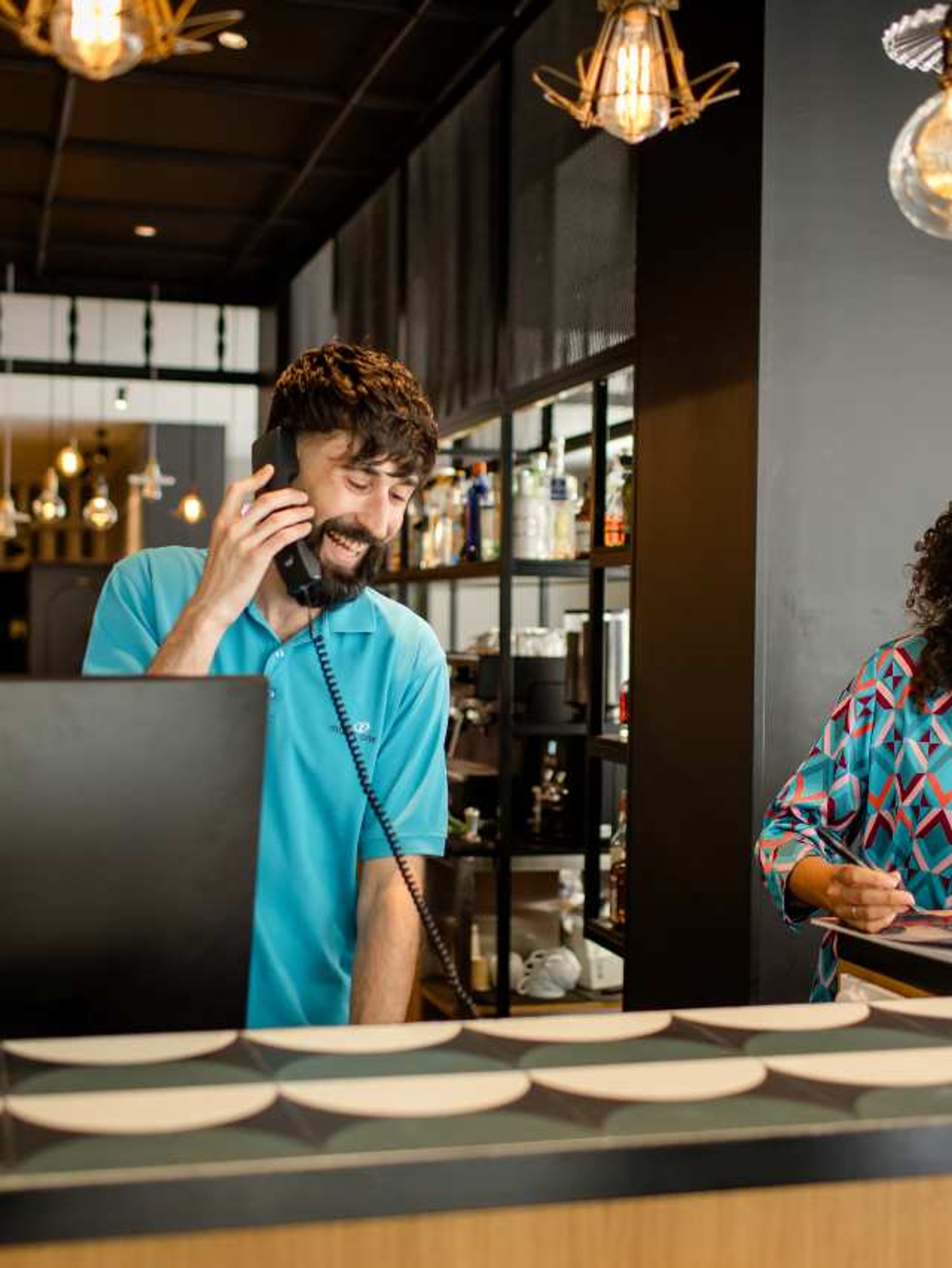 Designhotel Madrid Plaza de España Motel One Rezeption mit zwei lachenden Mitarbeitenden