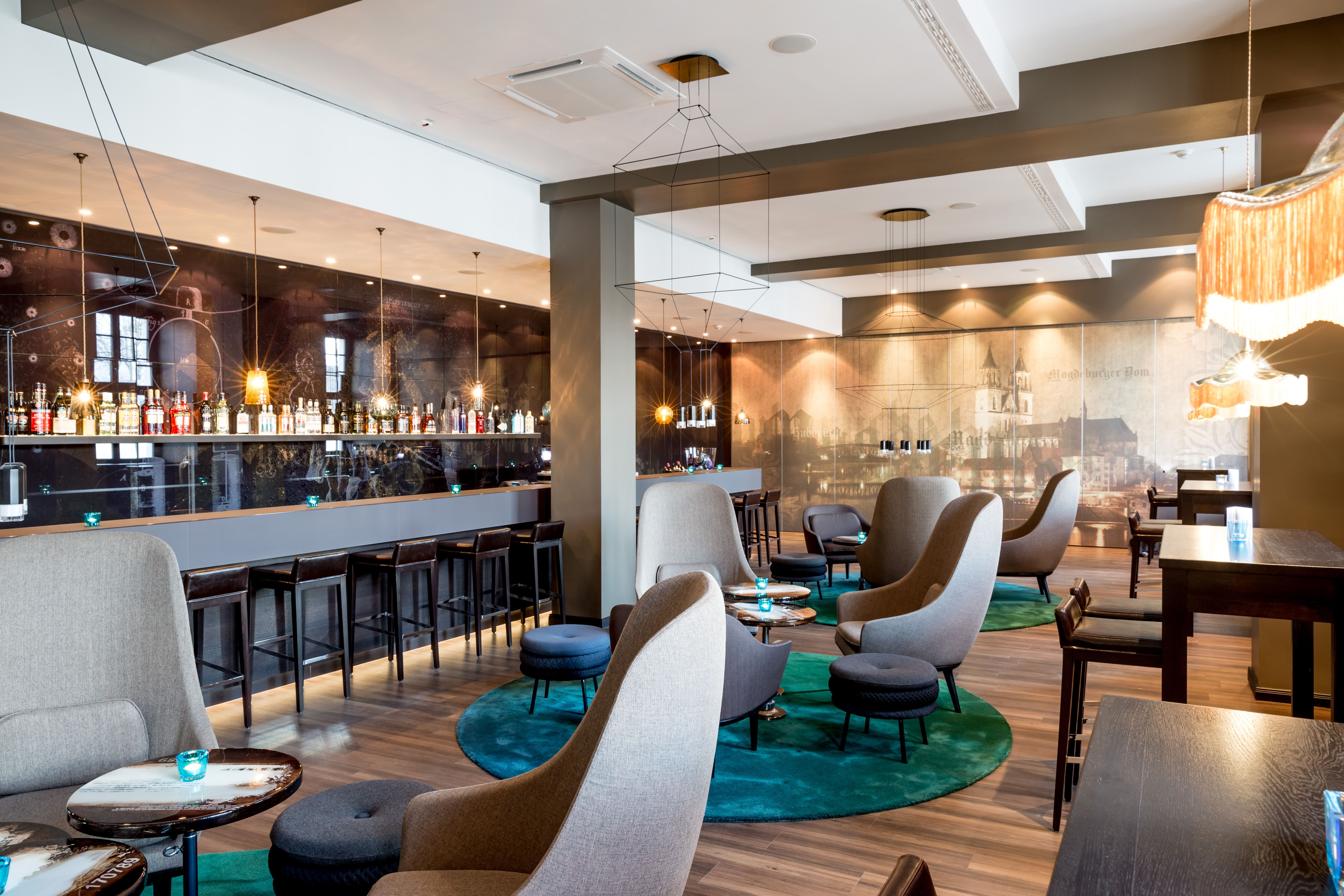 Hotel Magdeburg Motel One große Lounge mit mehreren Sesseln zum Verweilen sowie Bar im Hintergrund