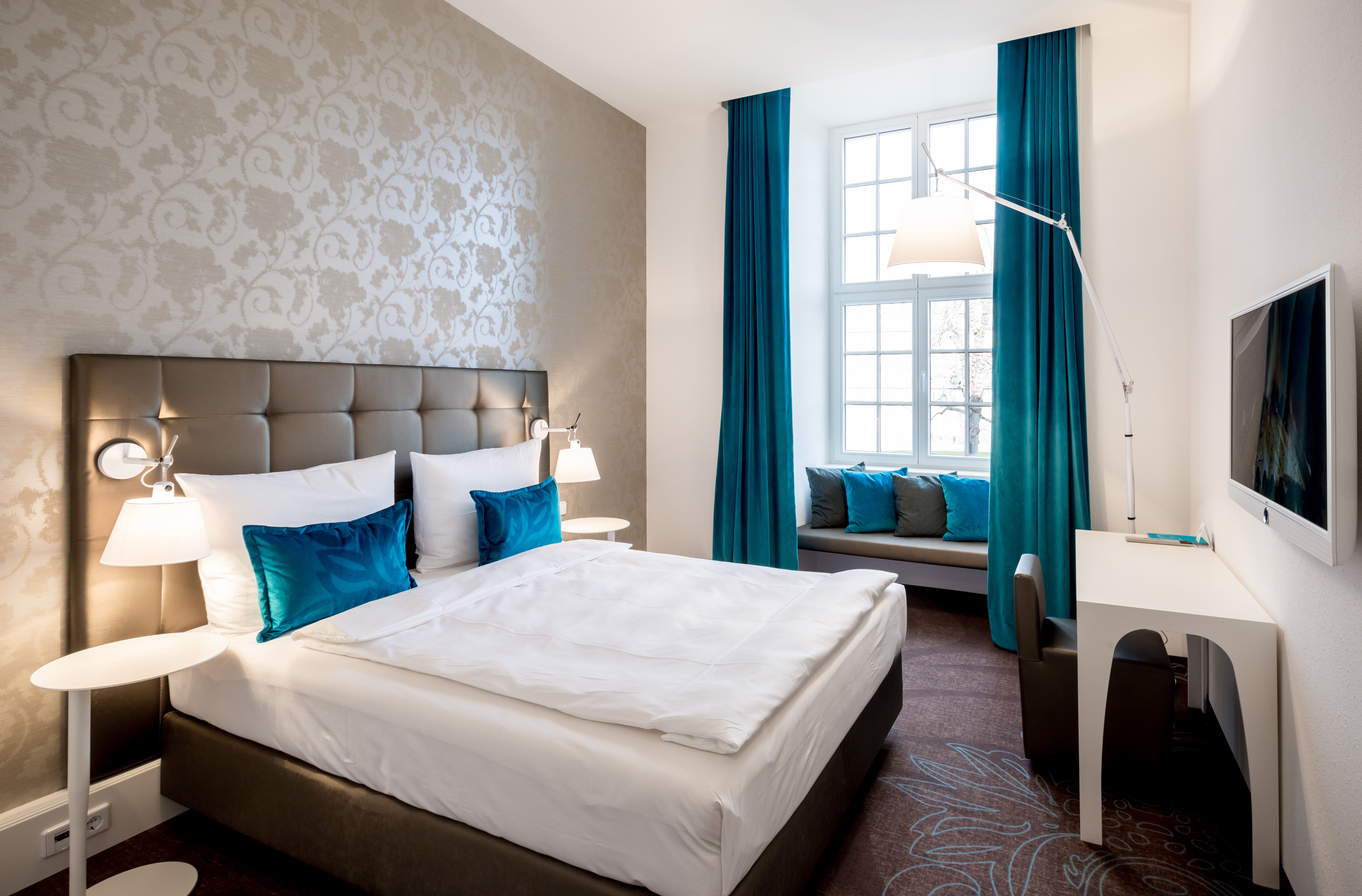 Hotel Magdeburg Motel One Schlafzimmer mit Doppelbett und einer Sitzbank vor dem großen Fenster