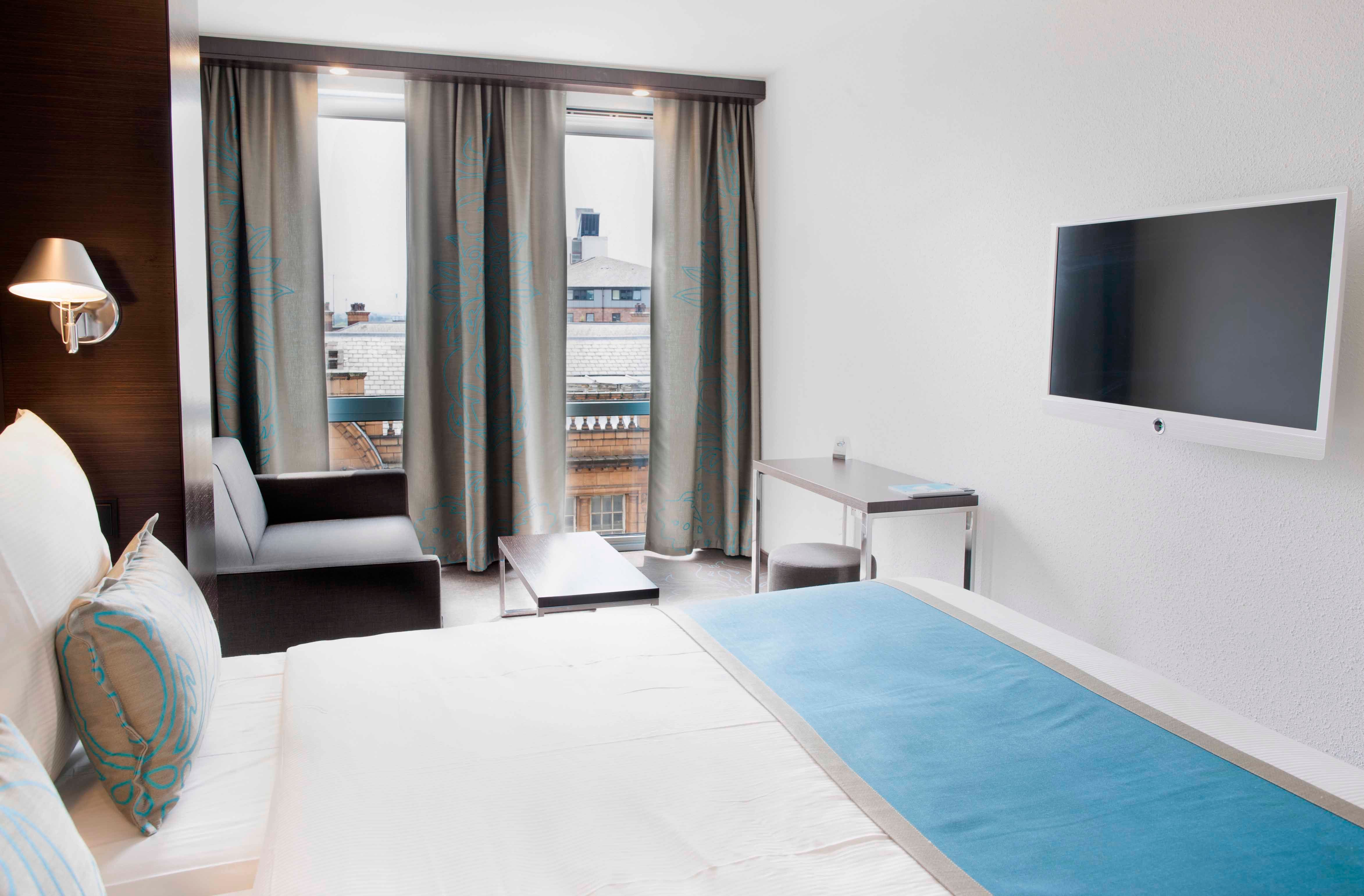 Designhotel Manchester Piccadilly Motel One Doppelbett, Sofa vor bodentiefem Fenster und TV an der Wand