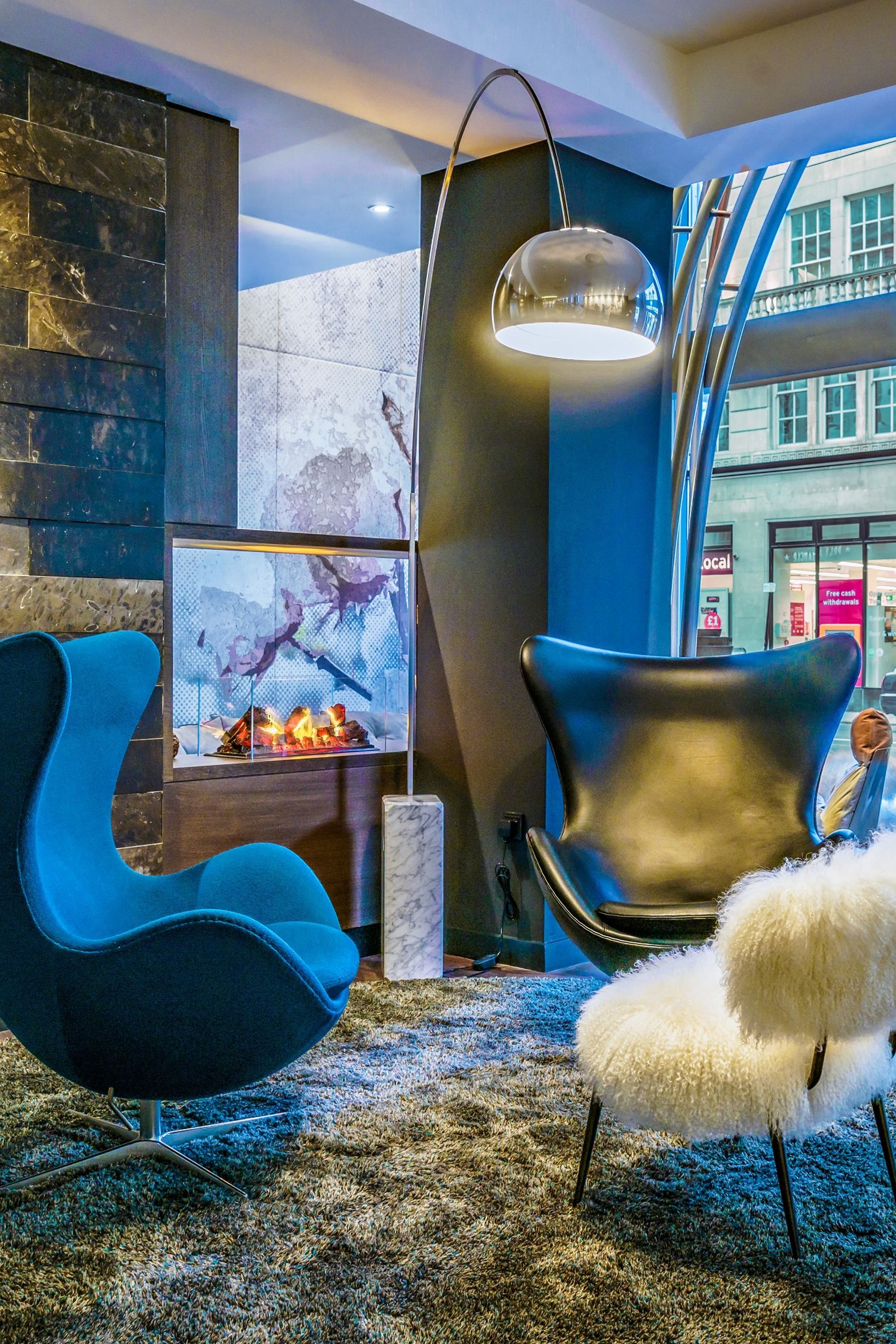 Hotel Manchester Royal Exchange Motel One zwei Egg chairs vor unechtem Kamin und großer Fensterfront