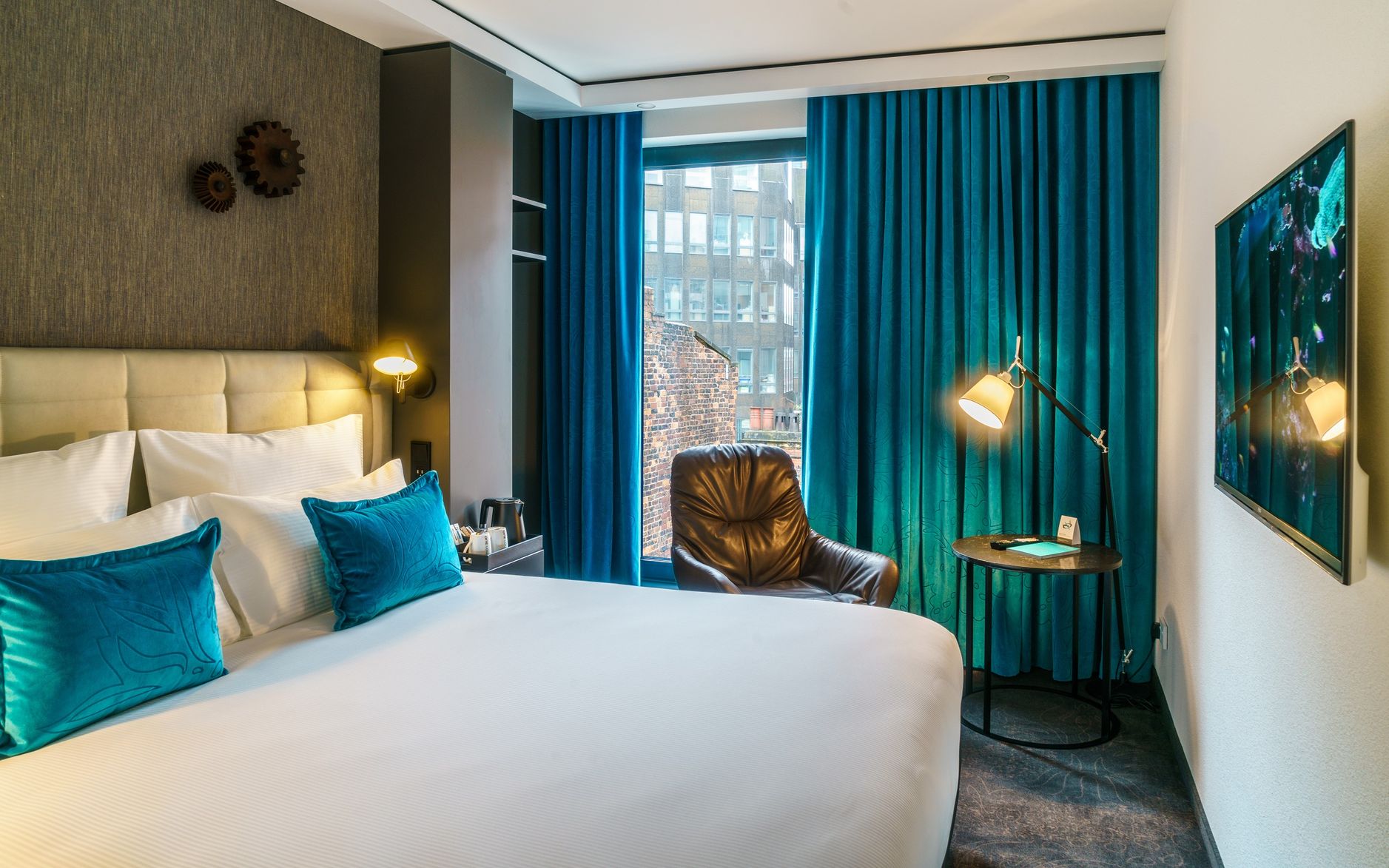 Designhotel Manchester Royal Exchange Motel One helles Zimmer mit Doppelbett, Sessel und Fernseher an der Wand
