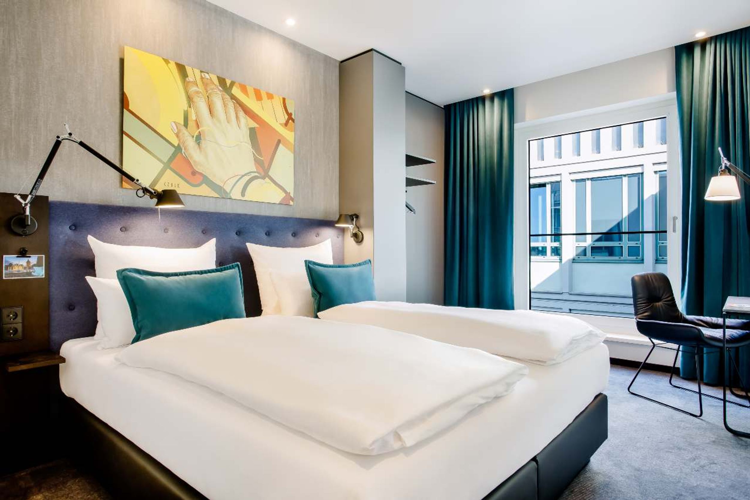 Hotel Mannheim Motel One Zimmer mit komfortablem Doppelbett und Sessel sowie Schreibtisch