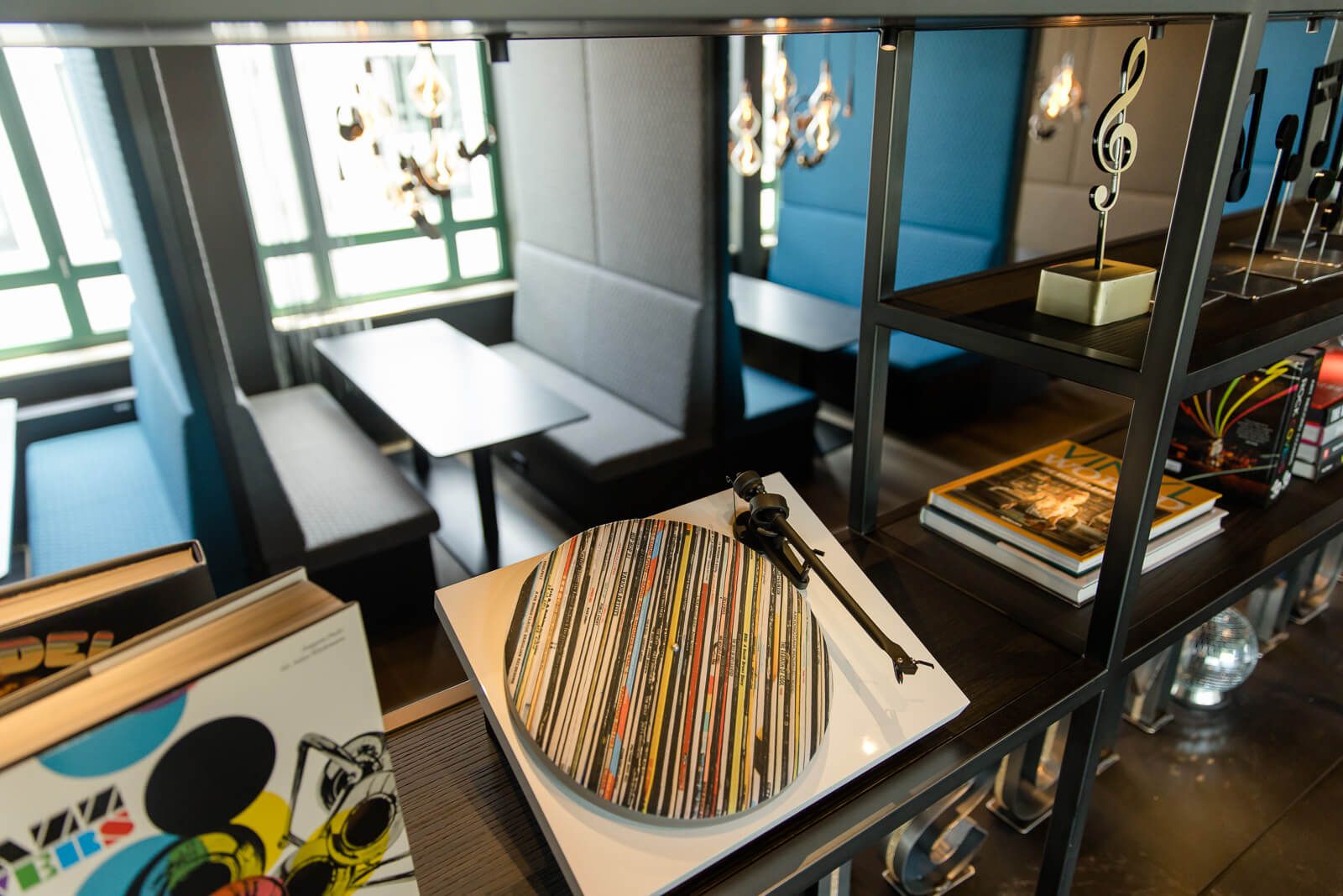 Hotel Mannheim Motel One Sitzgelegenheiten und offenes Regal mit Dekoration in Form eines Schallplattenspielers und Noten