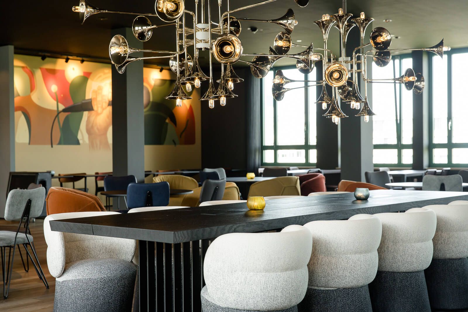 Hotel Mannheim Motel One helle Lounge mit Tischen und Stühlen sowie langem Tisch im Vordergrund