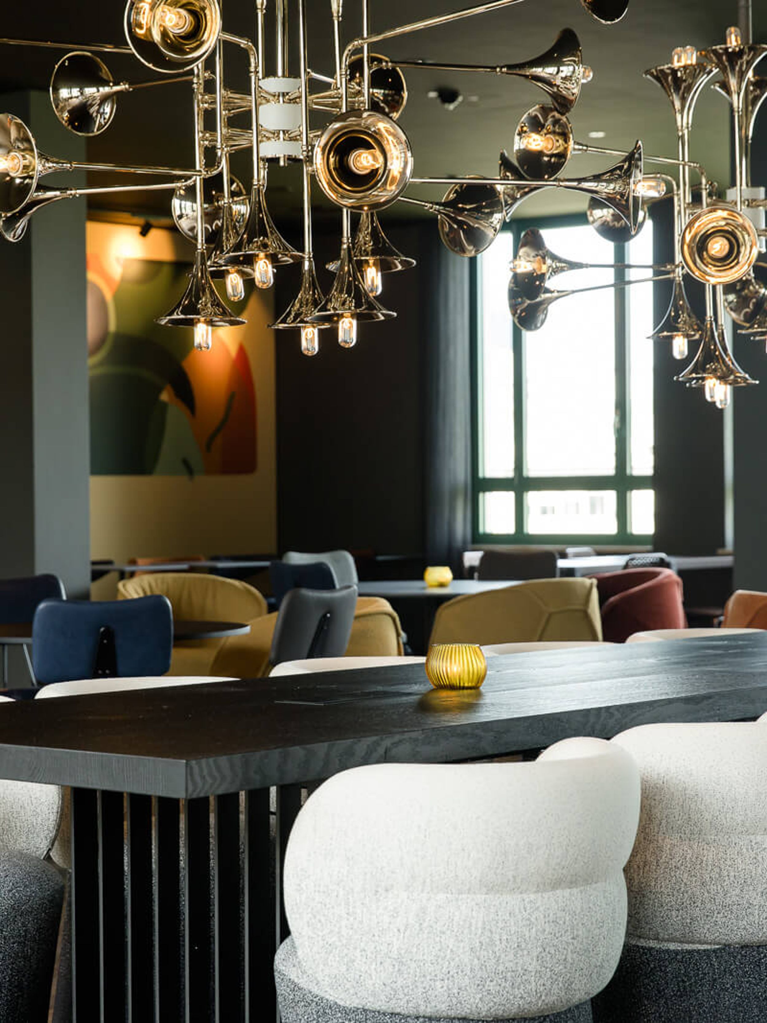 Hotel Mannheim Motel One helle Lounge mit Tischen und Stühlen sowie langem Tisch im Vordergrund