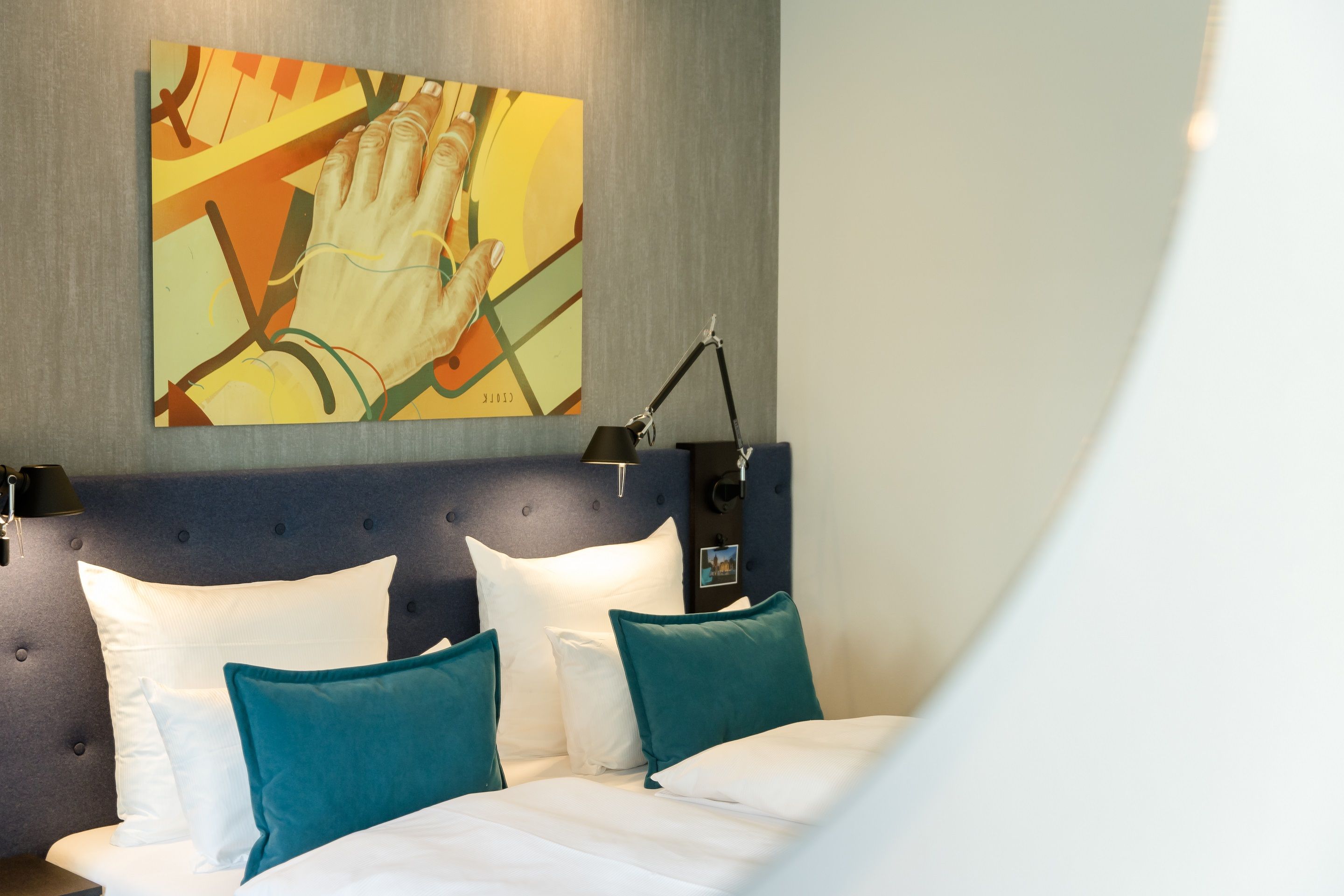 Designhotel Mannheim Motel One Blick durch Spiegel auf Doppelbett mit Zierkissen in türkis