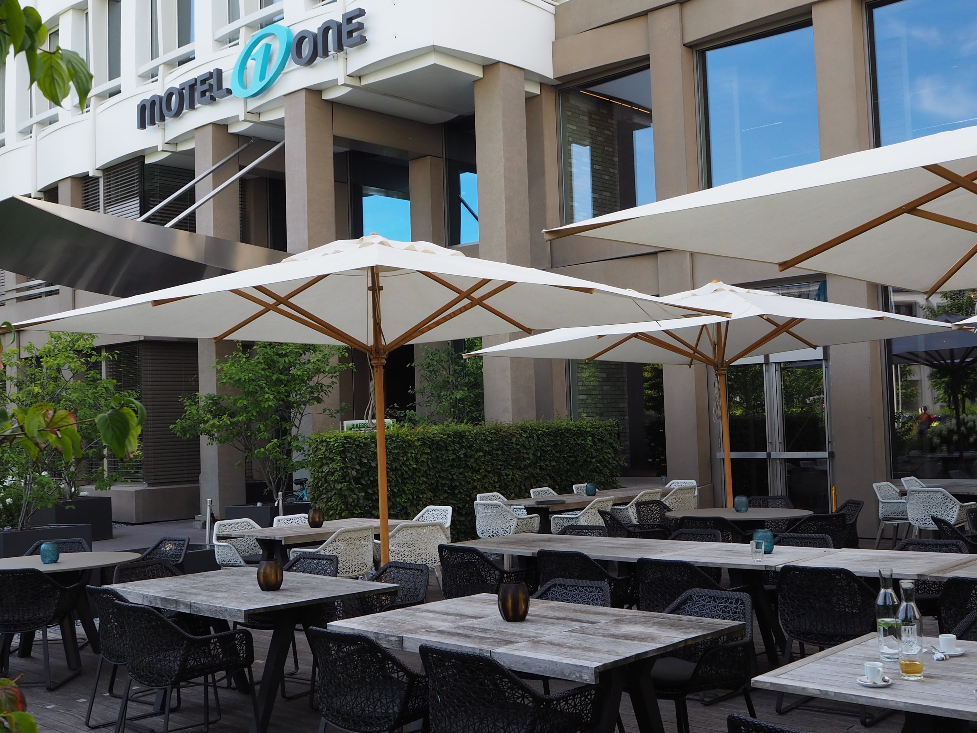 Designhotel München Campus Motel One Terrasse mit Stühlen und Tischen sowie Sonnenschirmen