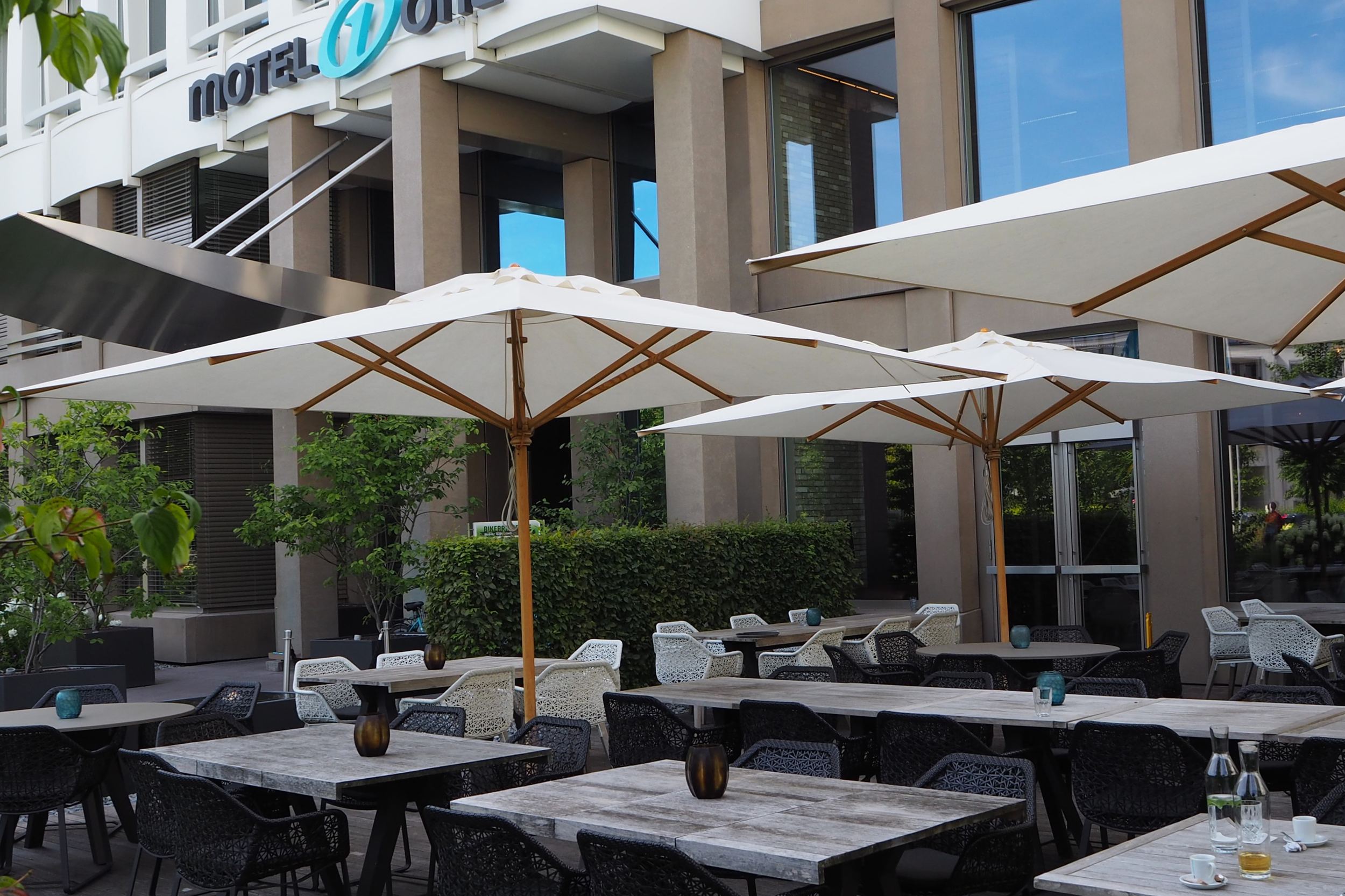 Designhotel München Campus Motel One Terrasse mit Stühlen und Tischen sowie Sonnenschirmen