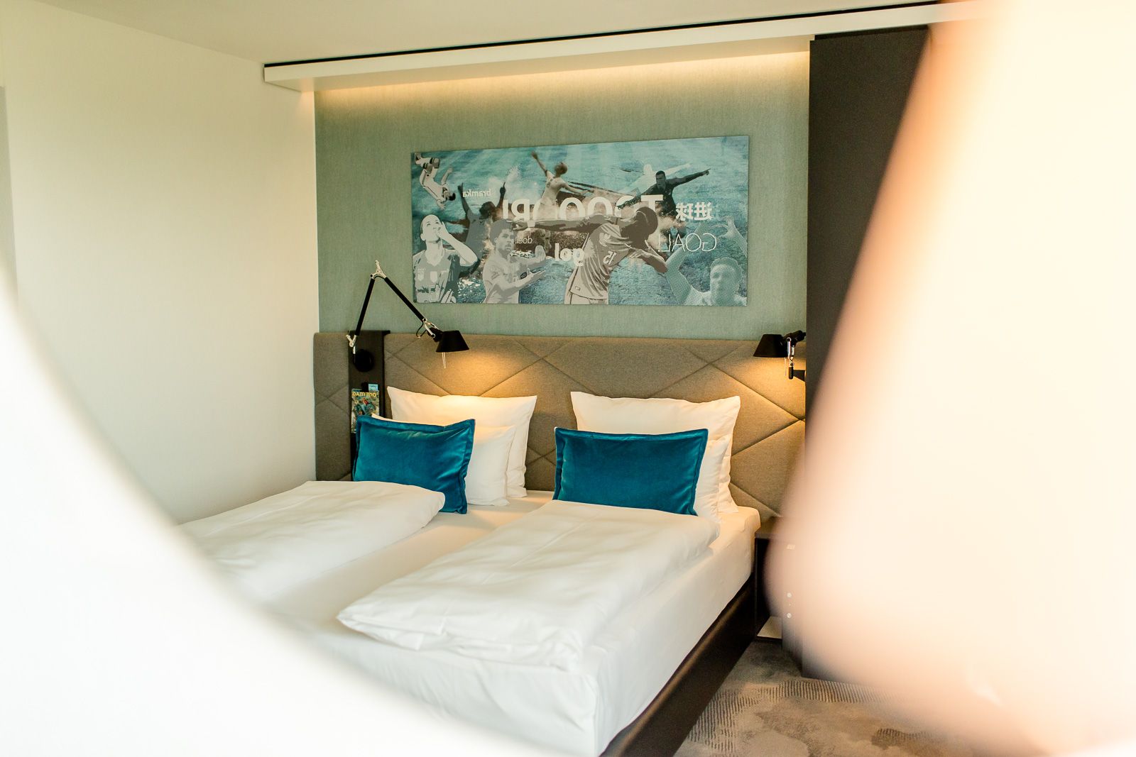 Designhotel Garching Motel One Zimmer mit Blick durch Spiegel auf komfortables Doppelbett mit Zierkissen