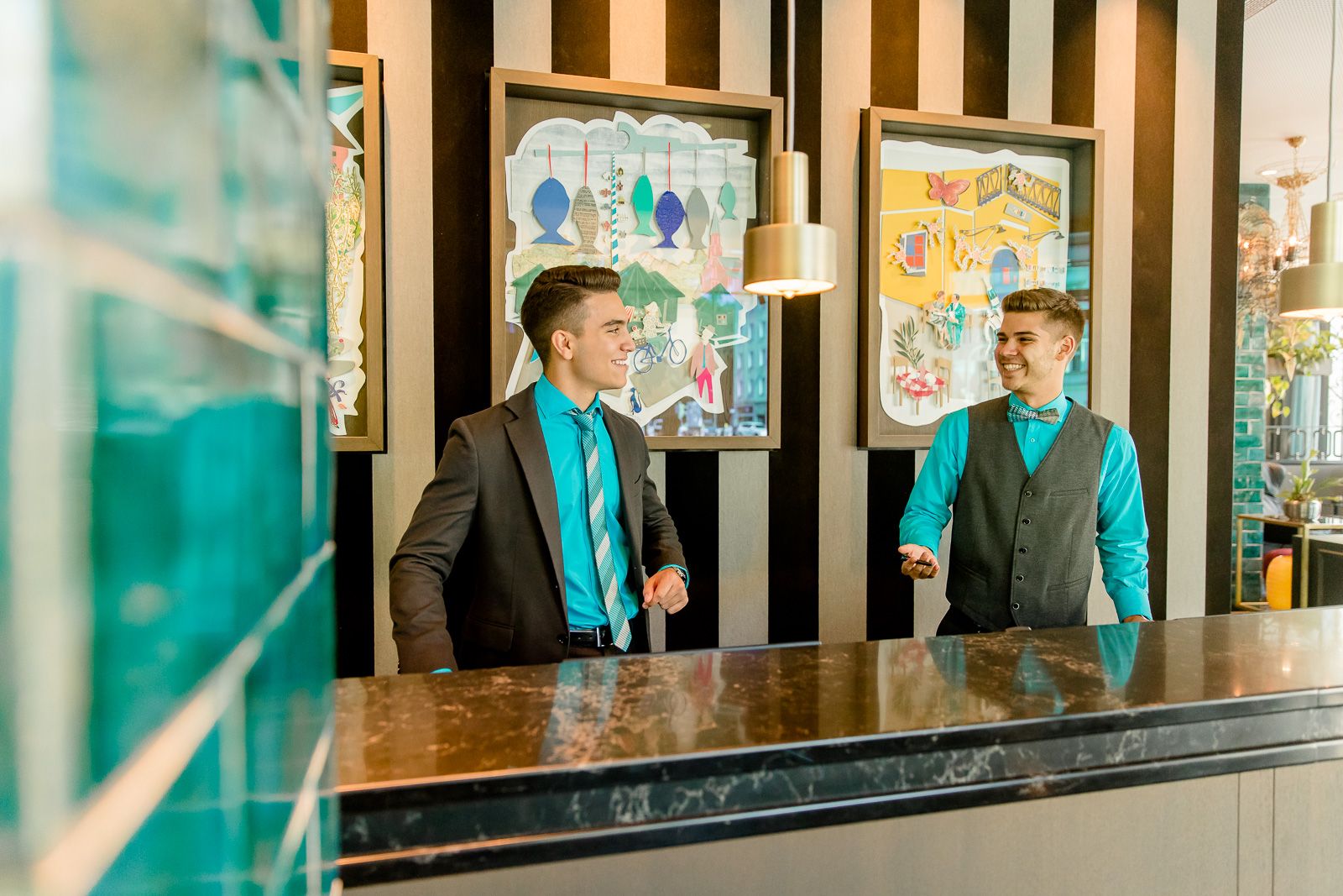 Designhotel München Haidhausen Motel One zwei lächelnde Mitarbeiter an der Rezeption