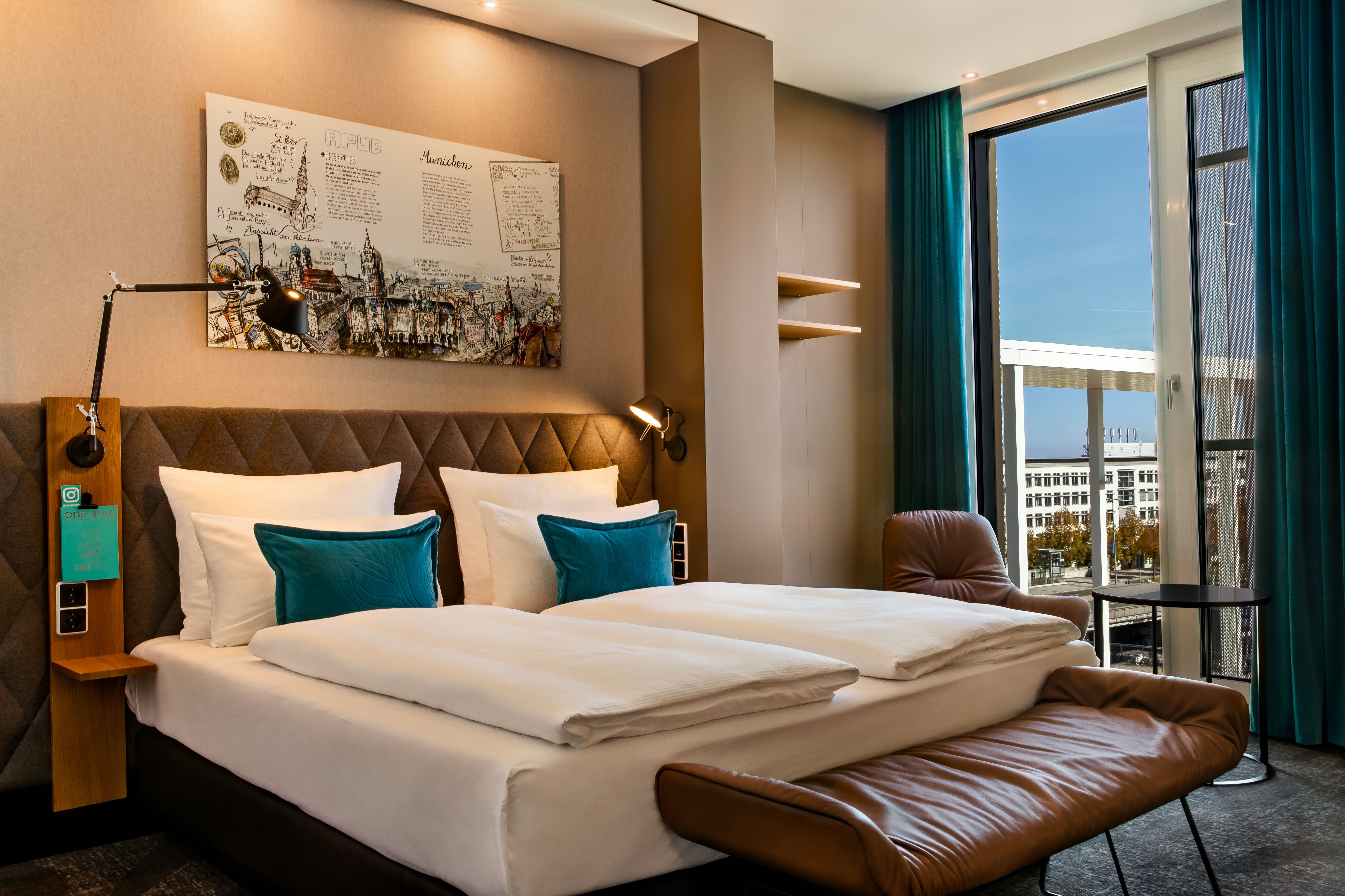 Designhotel München Messe Motel One lichtdurchflutetes Zimmer mit Doppelbett und bodentiefen Fenstern