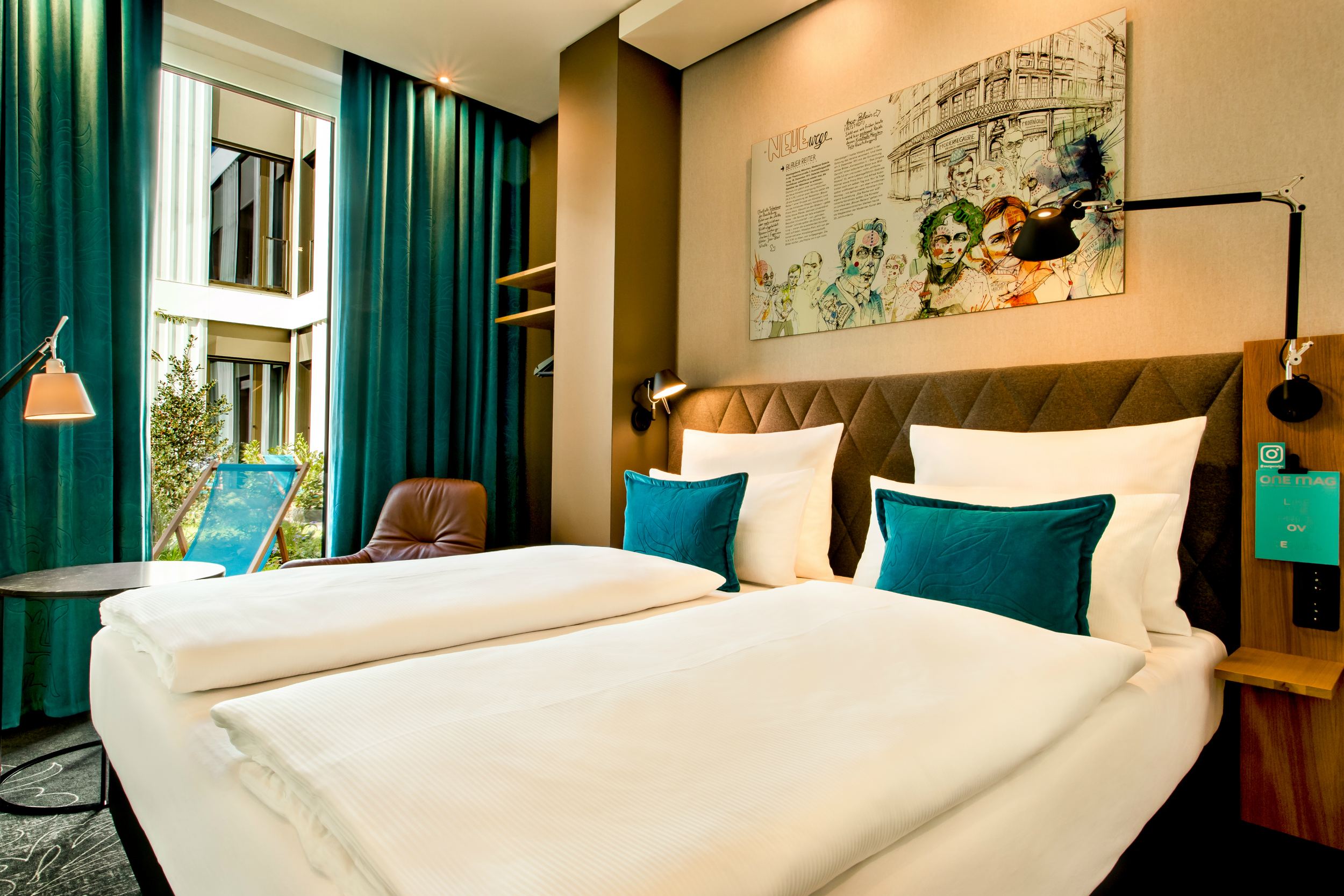 Designhotel München Messe Motel One helles Zimmer mit Doppelbett und Terrassenzugang mit Liegestuhl