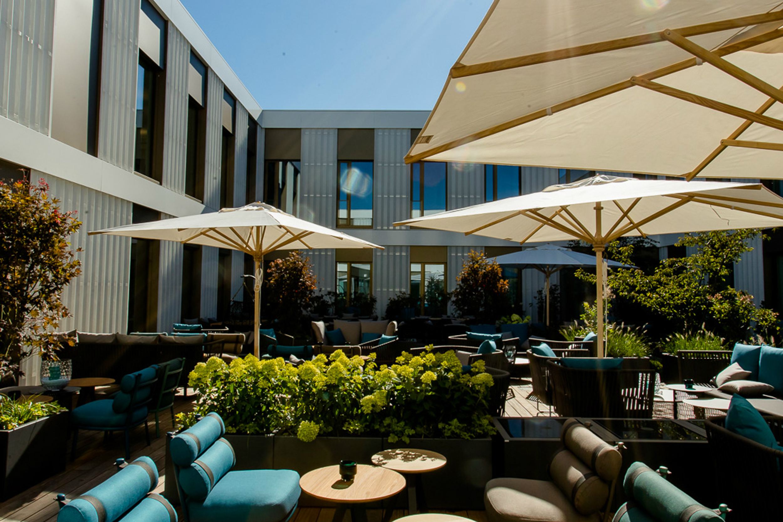 Designhotel München Messe Motel One großer und sonniger Außenbereich mit Sitzgelegenheiten und Sonnenschirmen