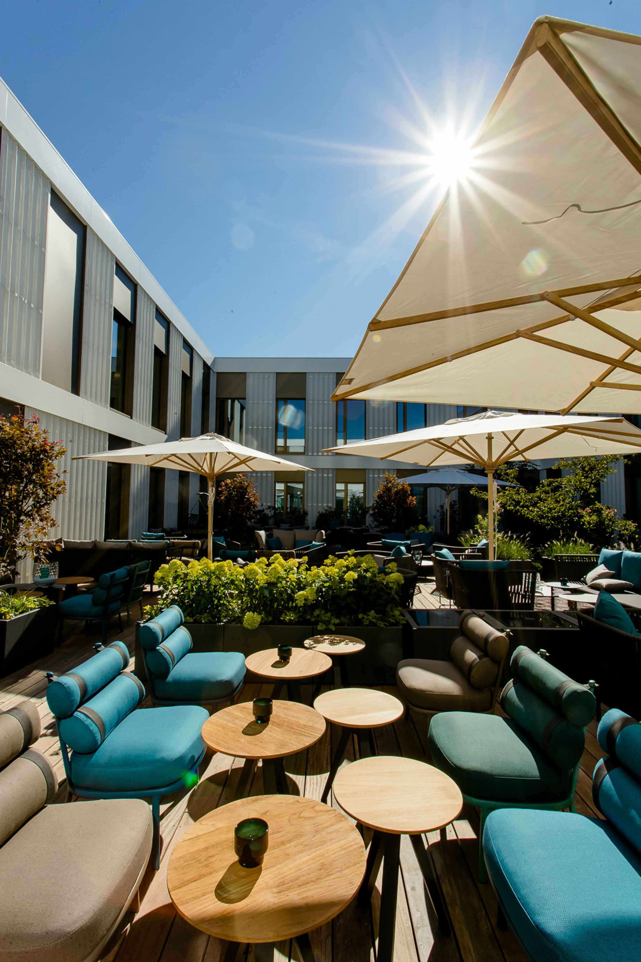 Designhotel München Messe Motel One großer und sonniger Außenbereich mit Sitzgelegenheiten und Sonnenschirmen