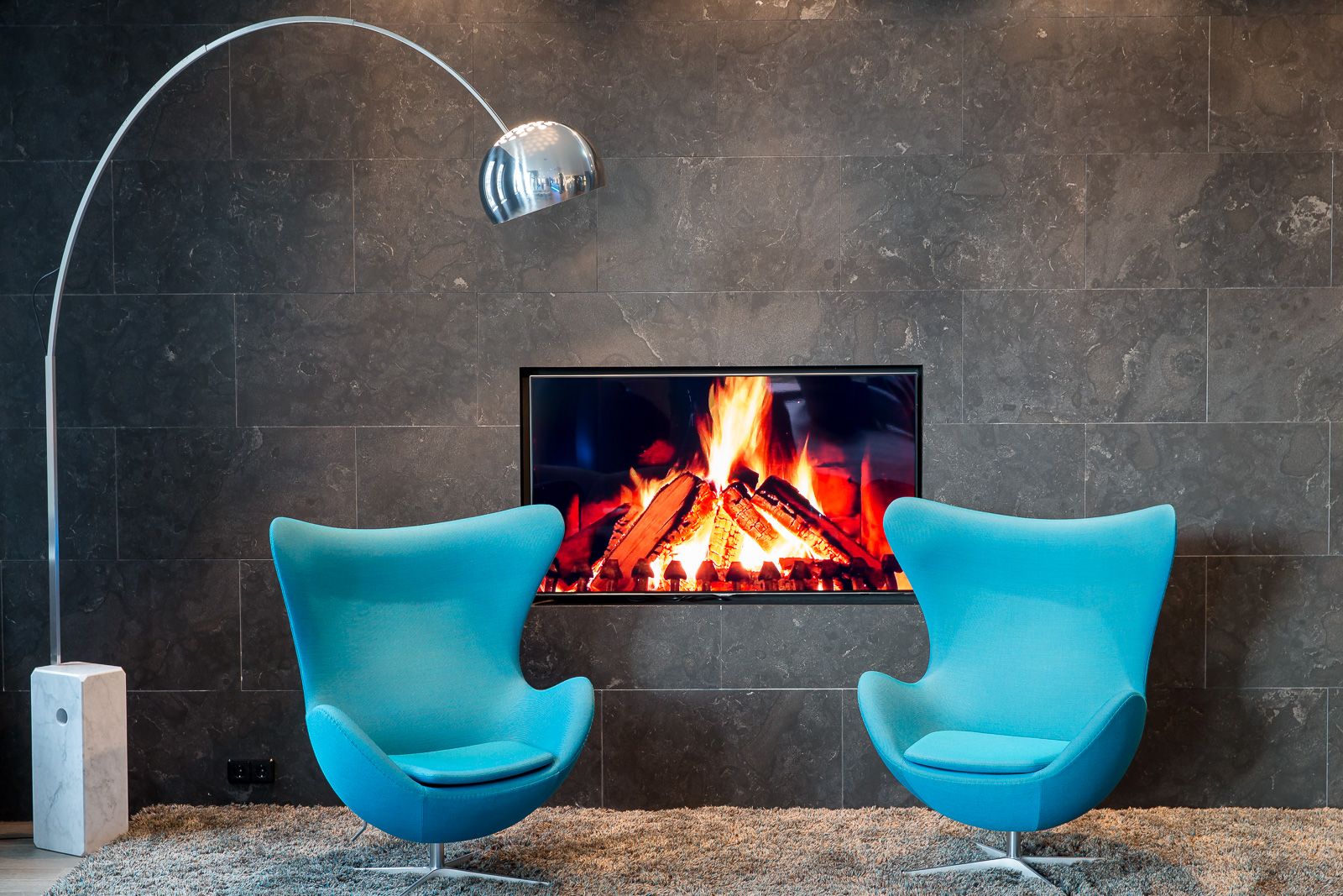 Design Hotel München Olympia Gate Motel One zwei Egg chairs vor TV mit Feuer