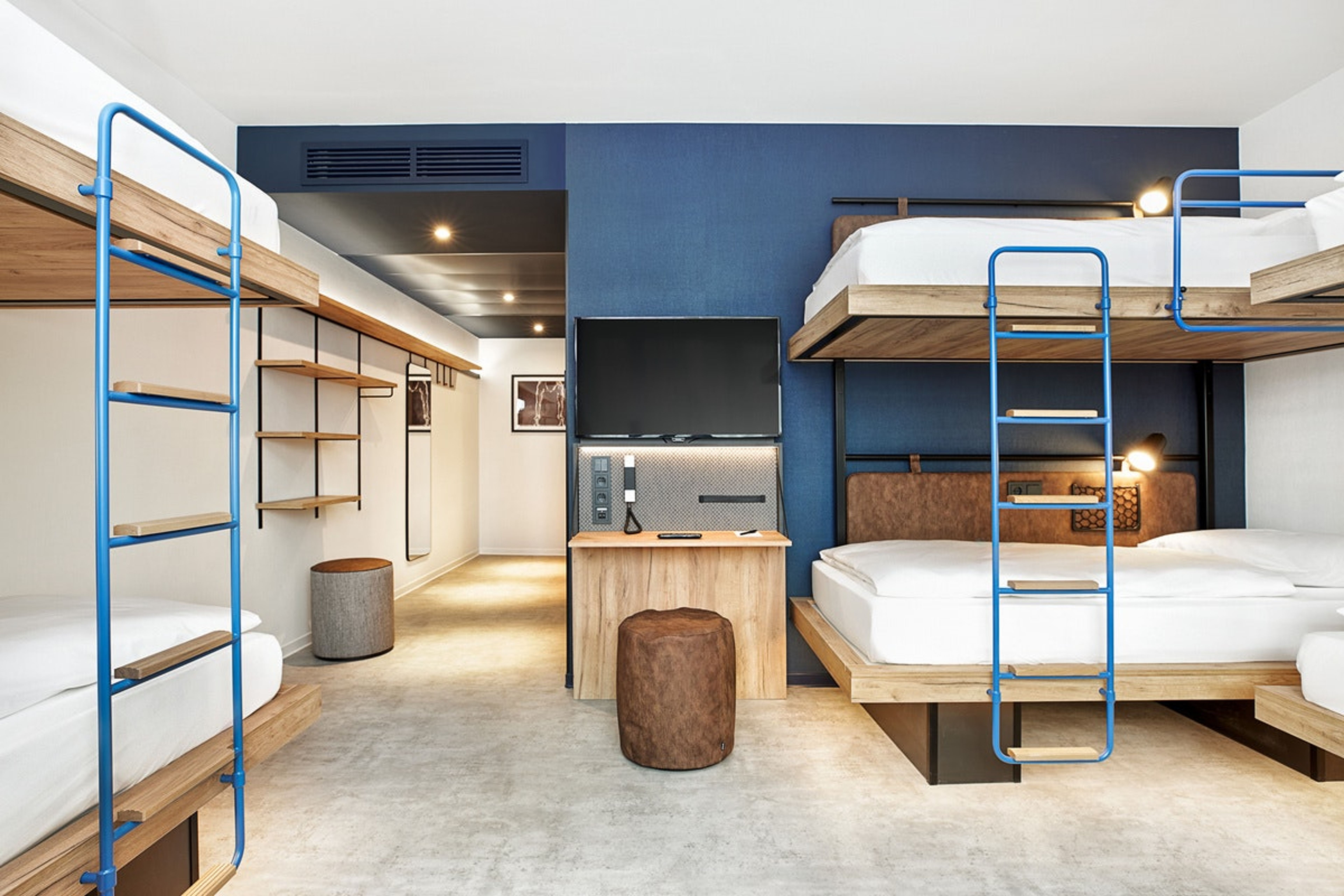 Modern eingerichtetes Mehrbettzimmer mit zwei Etagenbetten, neutralen Farben und Holzdetails, hellem Licht und einem Flachbildfernseher, das Platz für bis zu vier Personen bietet, ideal für Gruppen oder Familien. Modern eingerichtetes Mehrbettzimmer mit zwei Etagenbetten, neutralen Farben und Holzdetails, hellem Licht und einem Flachbildfernseher, das Platz für bis zu vier Personen bietet, ideal für Gruppen oder Familien.
