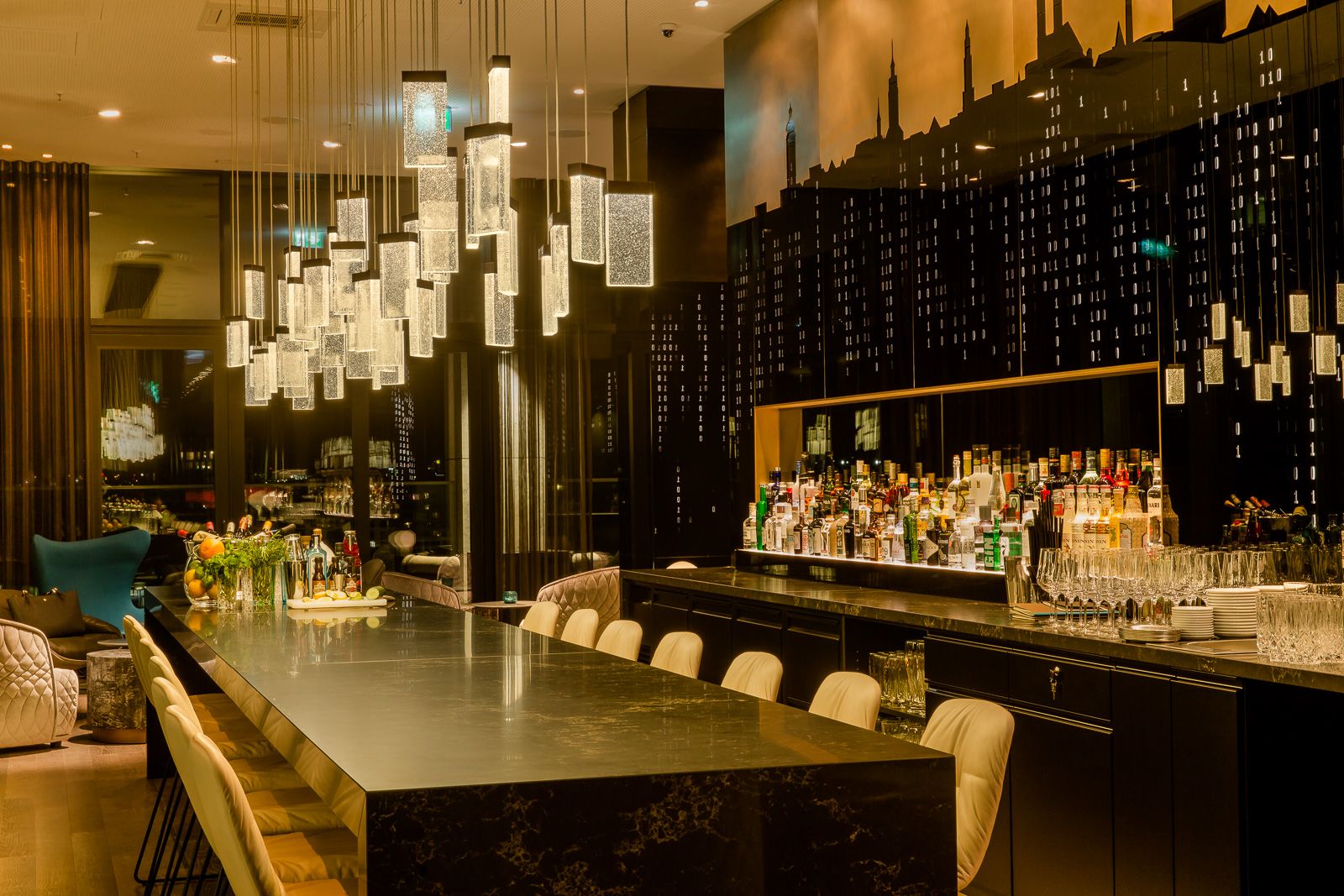 Hotel München Parkstadt Schwabing Motel One Bar am Abend mit langem Tisch und Stühlen