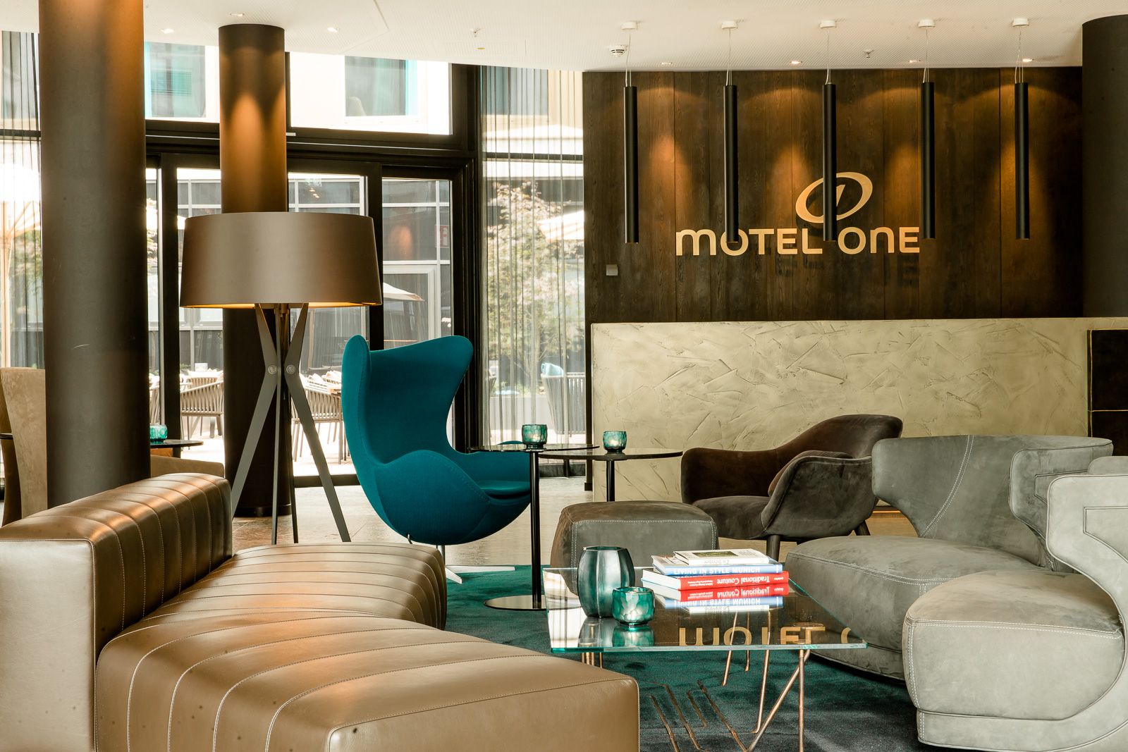 Hotel München Parkstadt Schwabing Motel One helle Lounge mit Sesseln, Egg Chair und Logo an der Wand