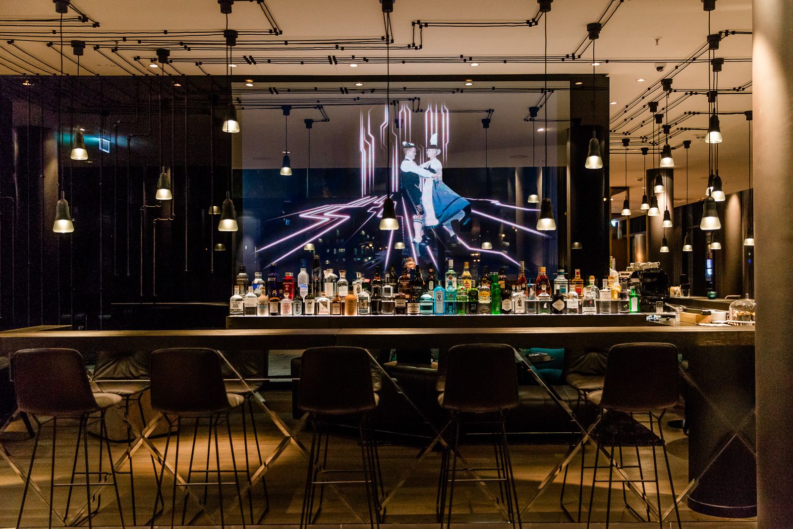 Designhotel München Parkstadt Schwabing Motel One Bar am Abend mit langem Tisch und Stühlen