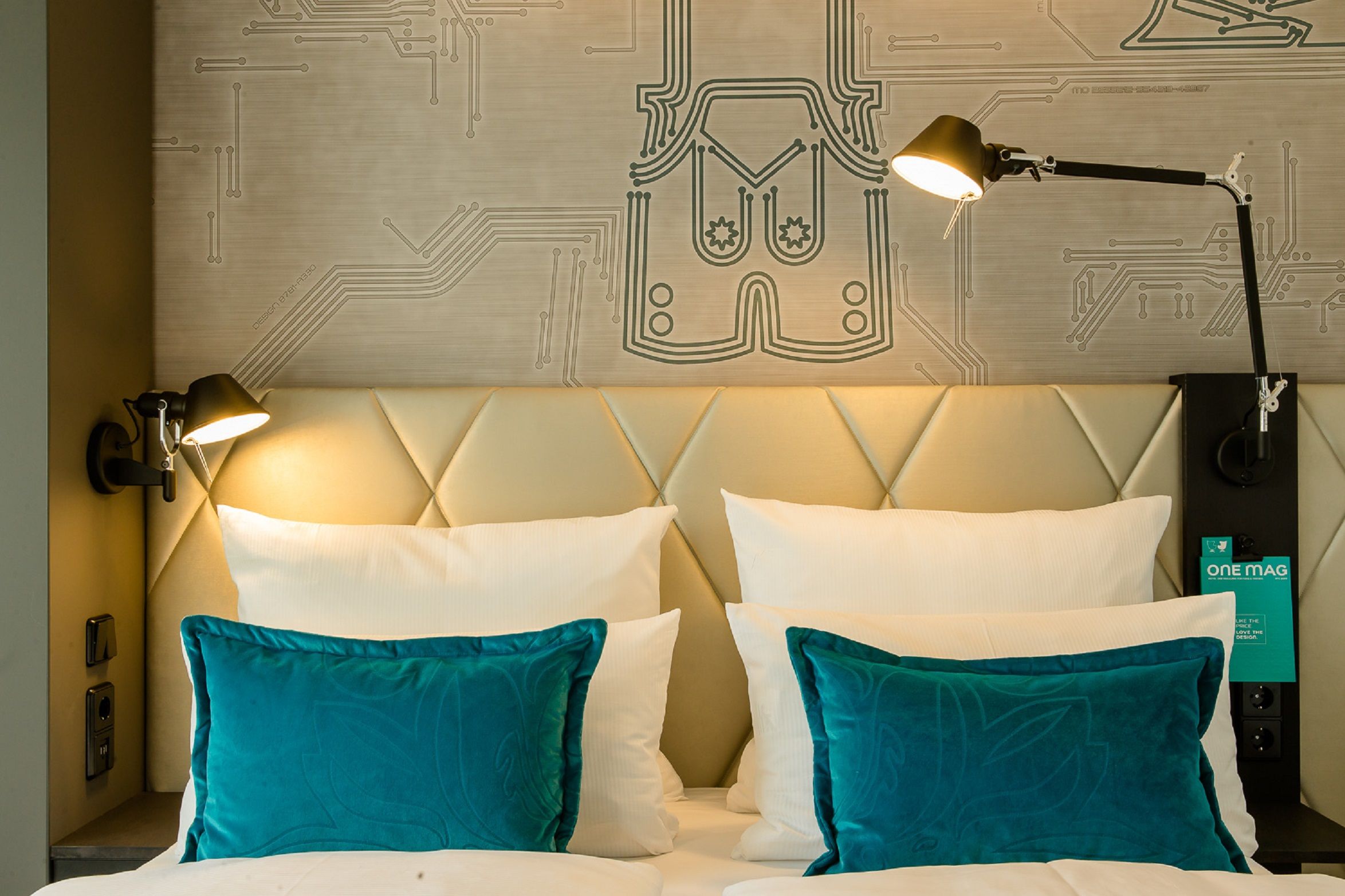 Designhotel München Parkstadt Schwabing Motel One Blick auf Doppelbett mit türkisen Zierkissen