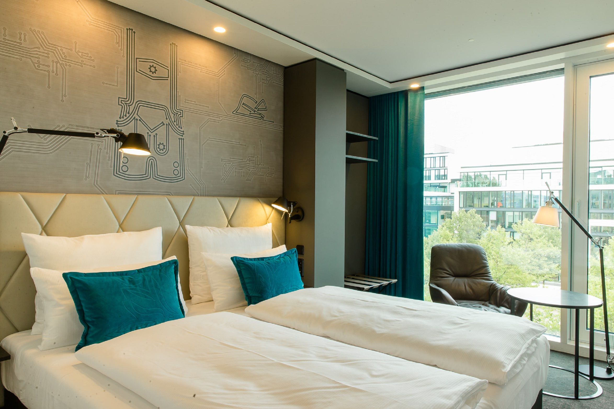 hotel München Parkstadt Schwabing Motel One double room with spacious bed and armchair in front of floor-to-ceiling window