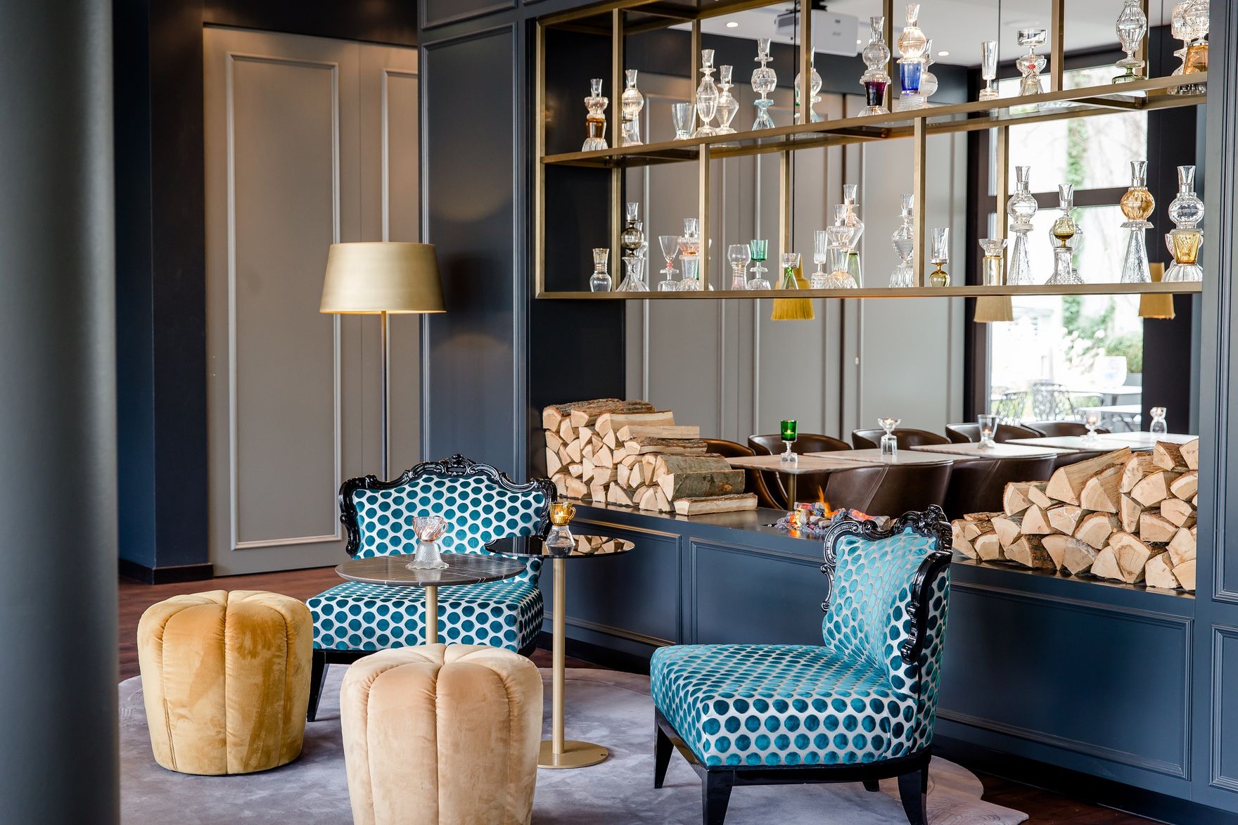 Hotel München Sendlinger Tor Motel One Sessel und Hocker vor offenem Regal mit Gläsern