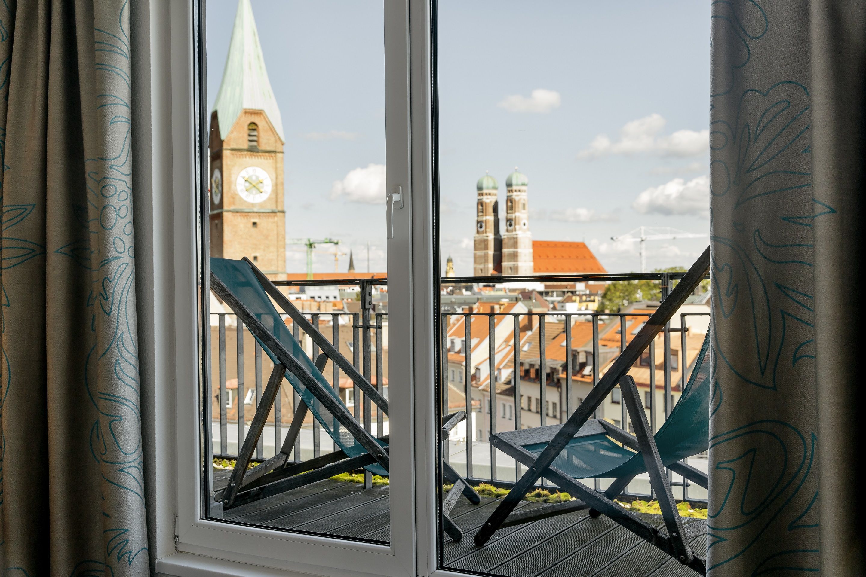 Designhotel München Sendlinger Tor Motel One Balkonzimmer mit zwei Liegestühlen und Aussicht über die Stadt
