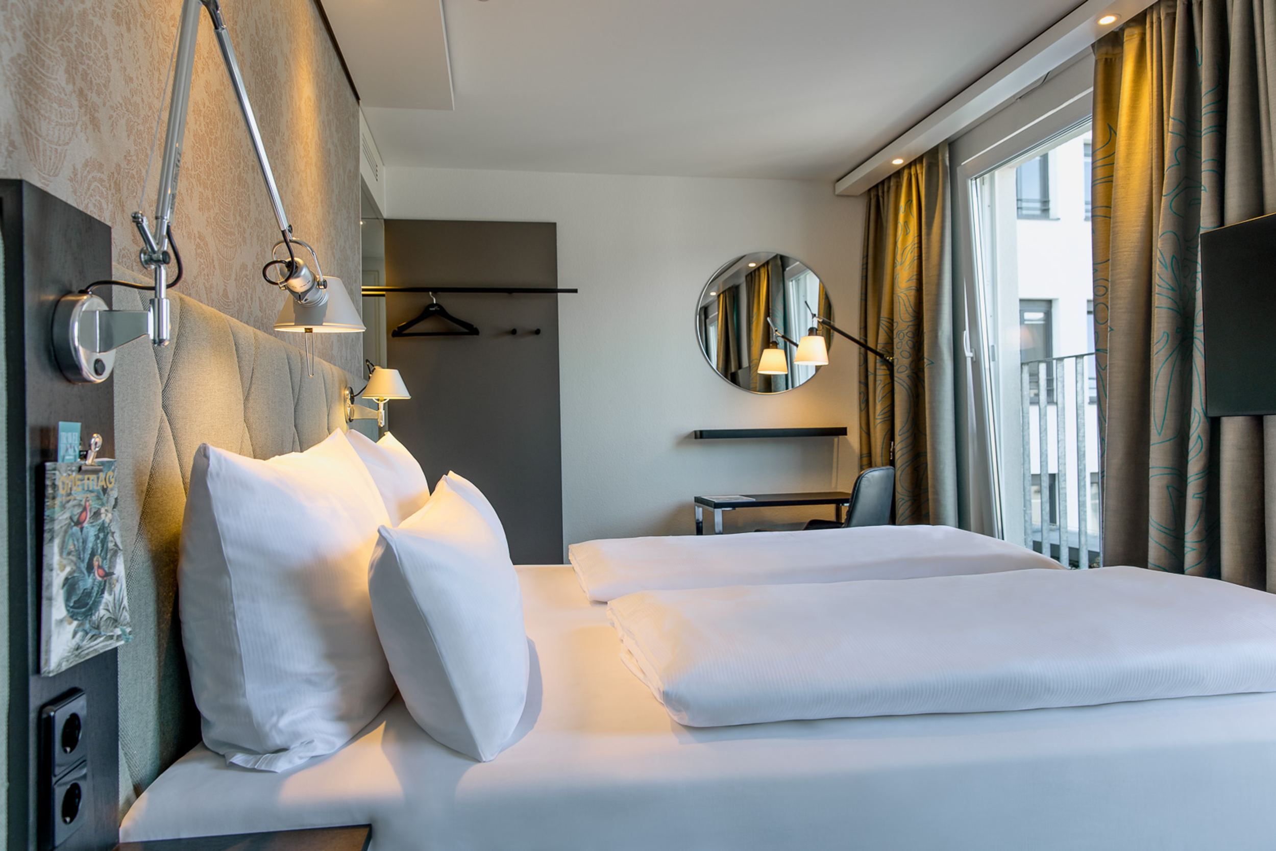 Designhotel München Sendlinger Tor Motel One seitlicher Blick über Doppelbett in hellen Raum