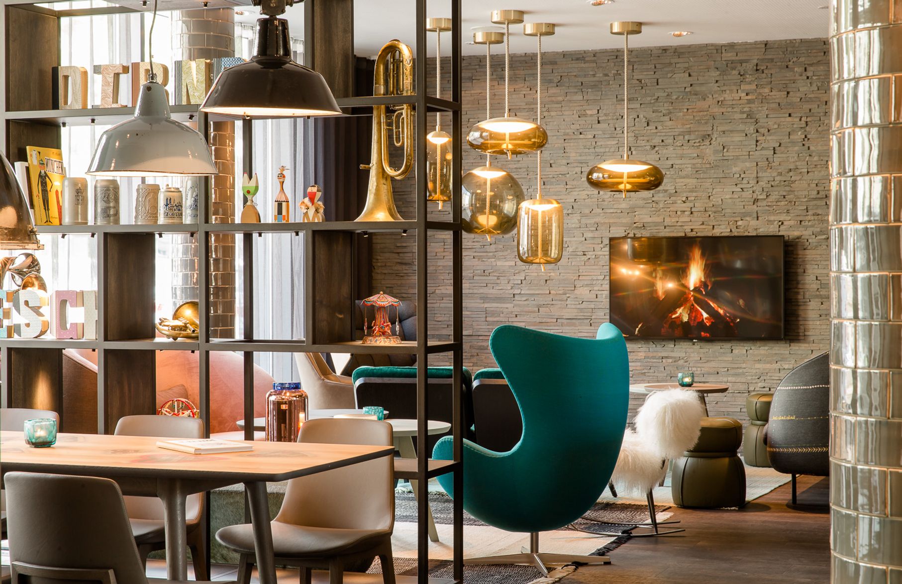Hotel München Westend Motel One lichtdurchflutete Lounge mit Egg chair und offenem Regal mit Dekoration