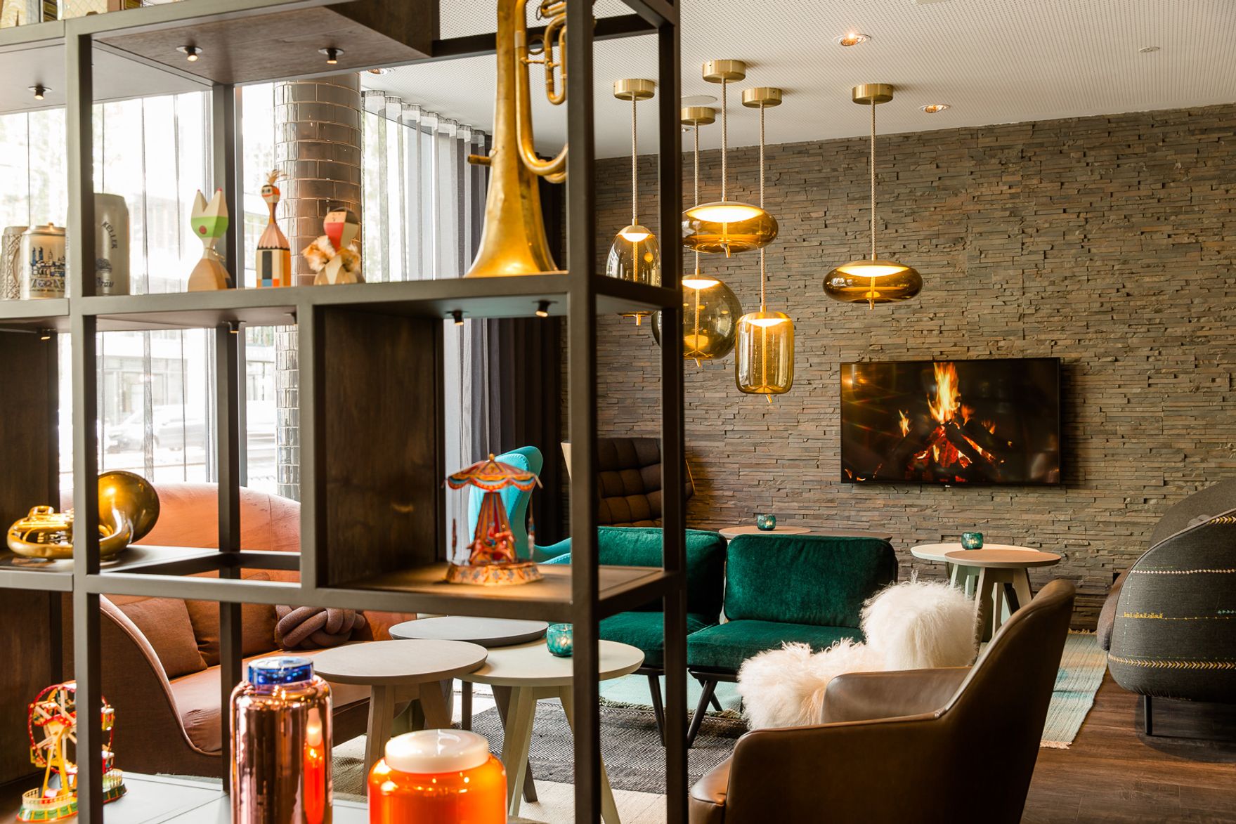 Hotel München Westend Motel One lichtdurchflutete Lounge mit Sesseln sowie Fernseher an der Wand