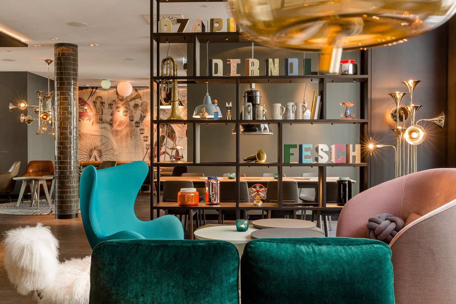 Hotel München Westend Motel One helle Lounge mit Sesseln und offenem Regal mit Dekoration