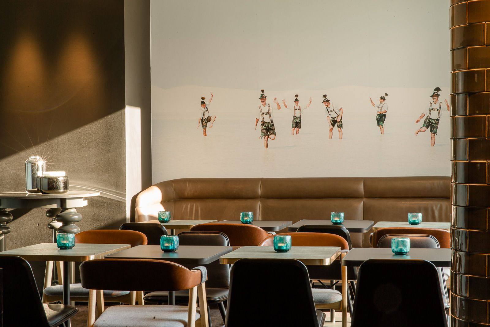 Designhotel München Westend Motel One mehrere Sitzgelegenheiten in hellem Raum sowie Gemälde an der Wand
