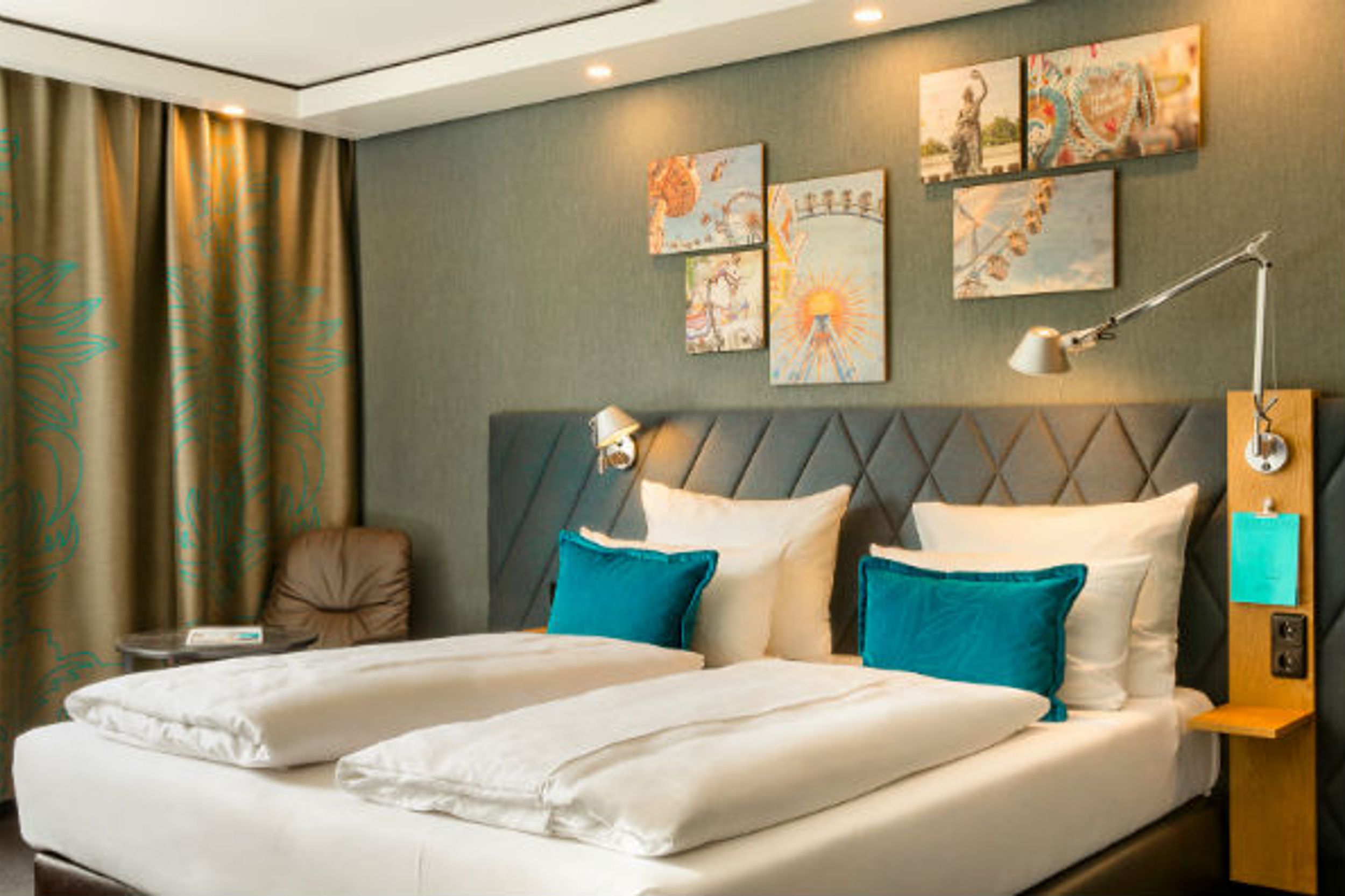 Designhotel München Westend Motel One Zimmer mit Doppelbett und Zierkissen sowie Sessel