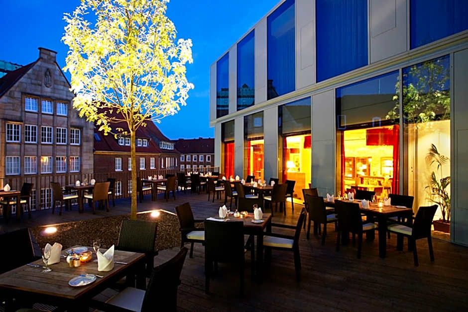 Außenbereich eines modernen Hotels mit stilvoller Terrasse, gedeckten Tischen und warmem Licht, ideal für entspanntes Abendessen unter klarem Nachthimmel.