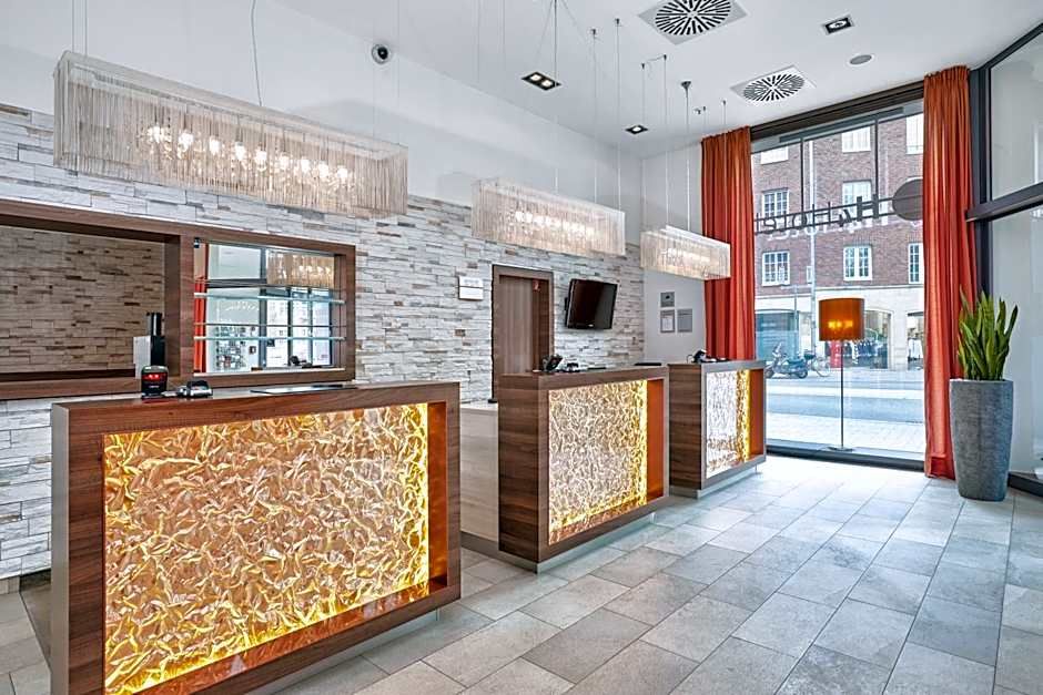 Helle und moderne Hotellobby mit beleuchteter Rezeption aus Holz und Stein, großen Fenstern für Tageslicht und roten Vorhängen, die eine einladende Atmosphäre schaffen.